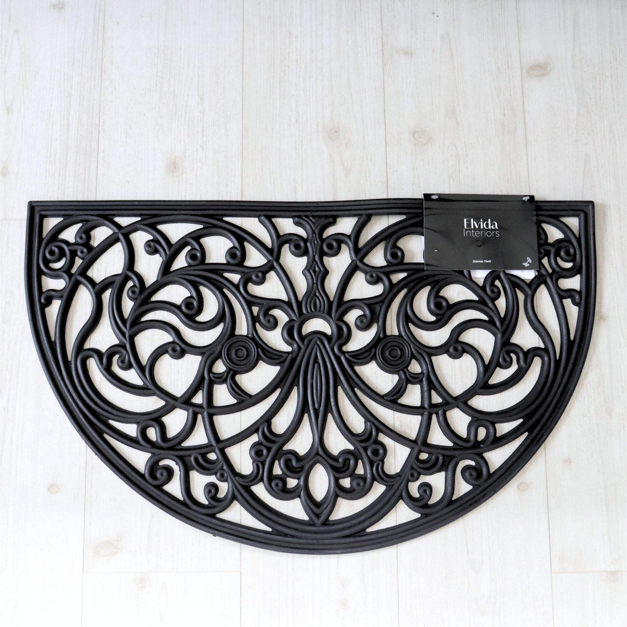 Decorative black metal half-circle design on a light wooden floor with 'Elvida Interiors' branding.