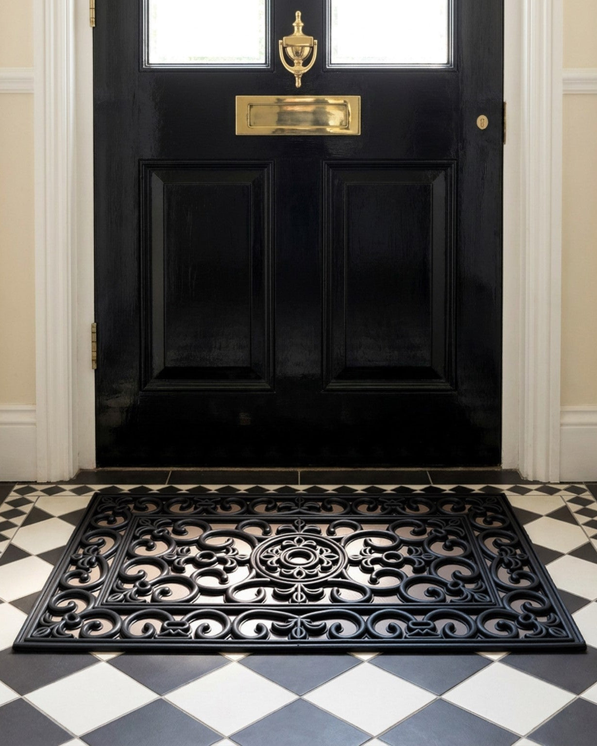 Black door with gold handle and mail slot, black decorative mat on checkered floor