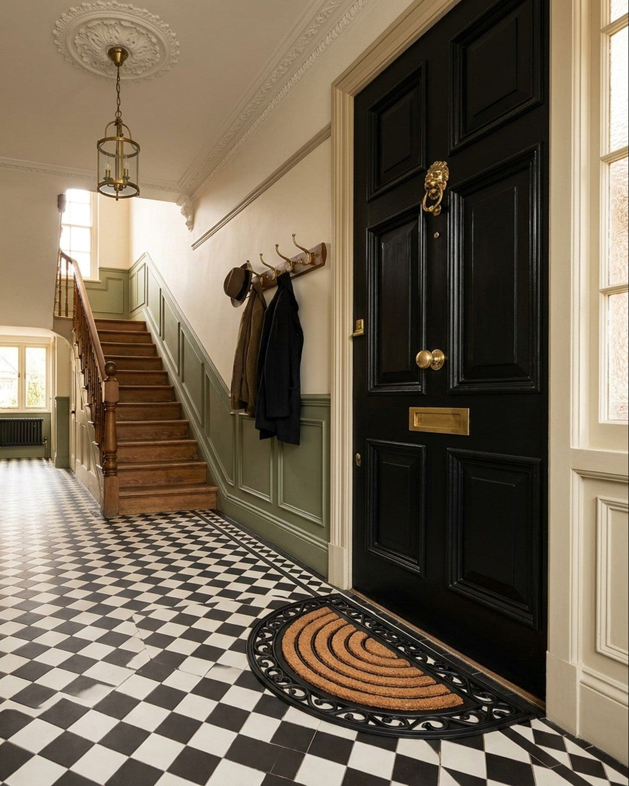 Stylish hallway with black door, checkered floor, and staircase