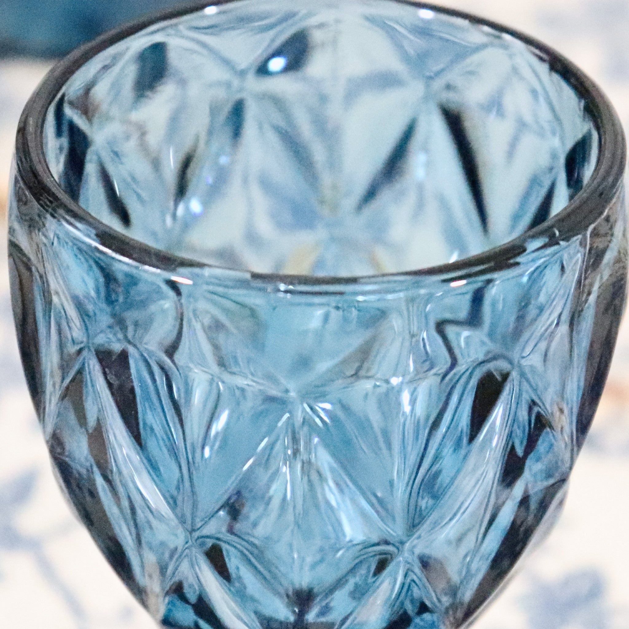 Blue glass vase with diamond pattern on a white background
