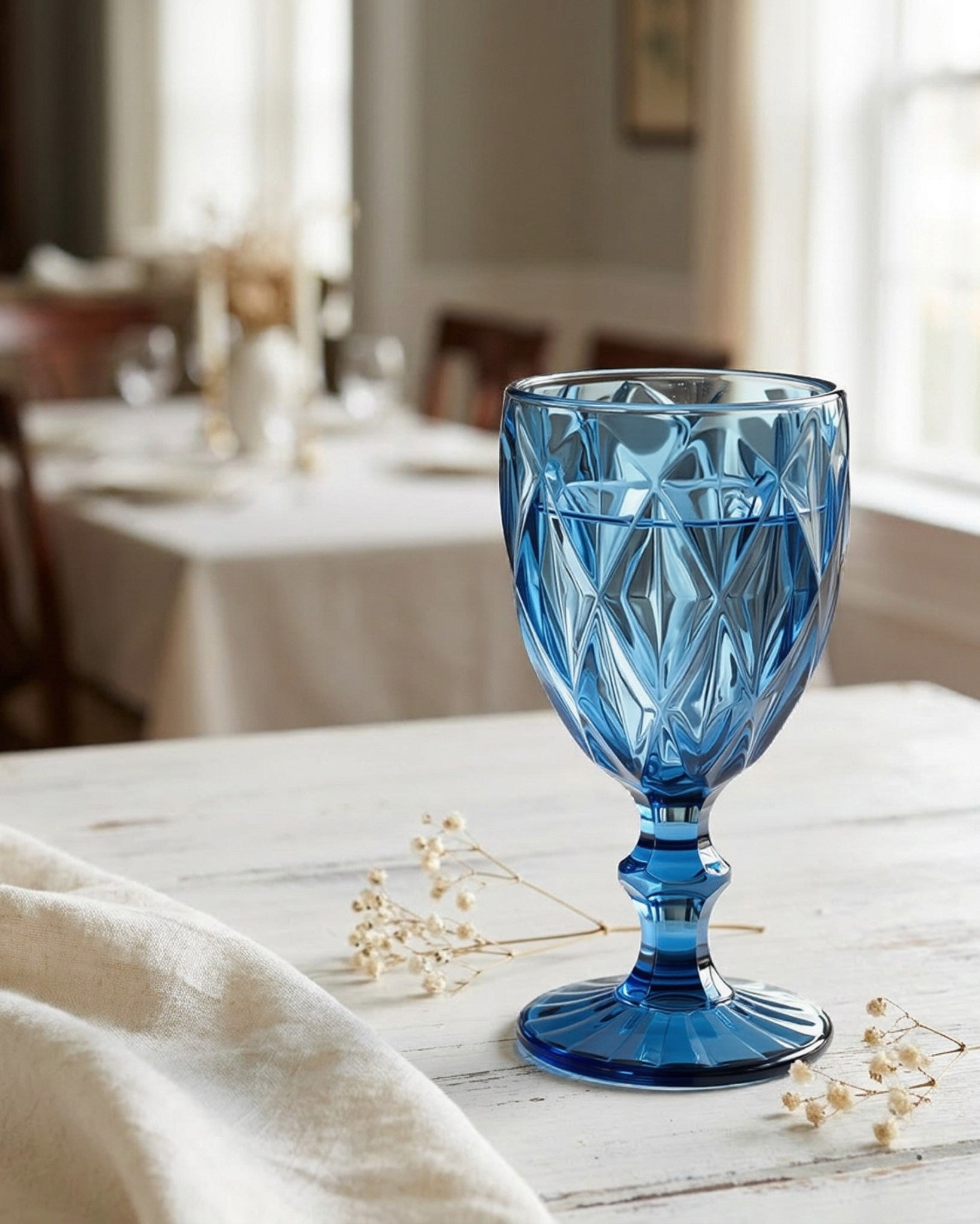 Blue glass goblet on a table with a blurred background of a room.