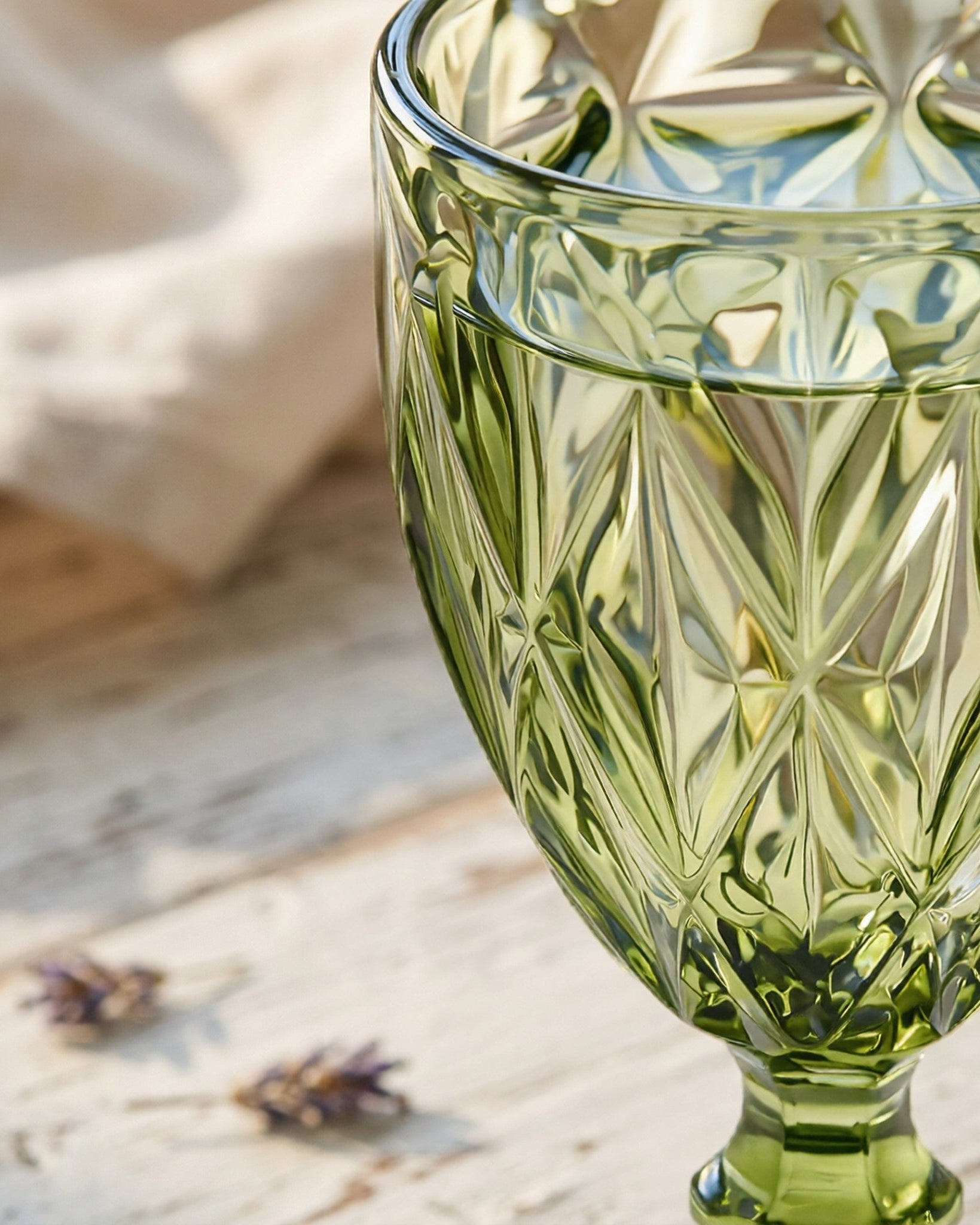 Green glass goblet with intricate patterns on a wooden surface