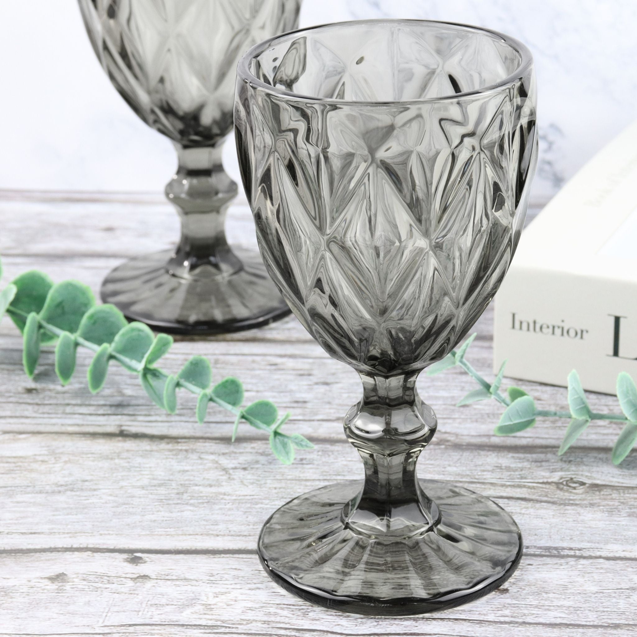 Decorative grey glass goblet on a wooden surface with a white background