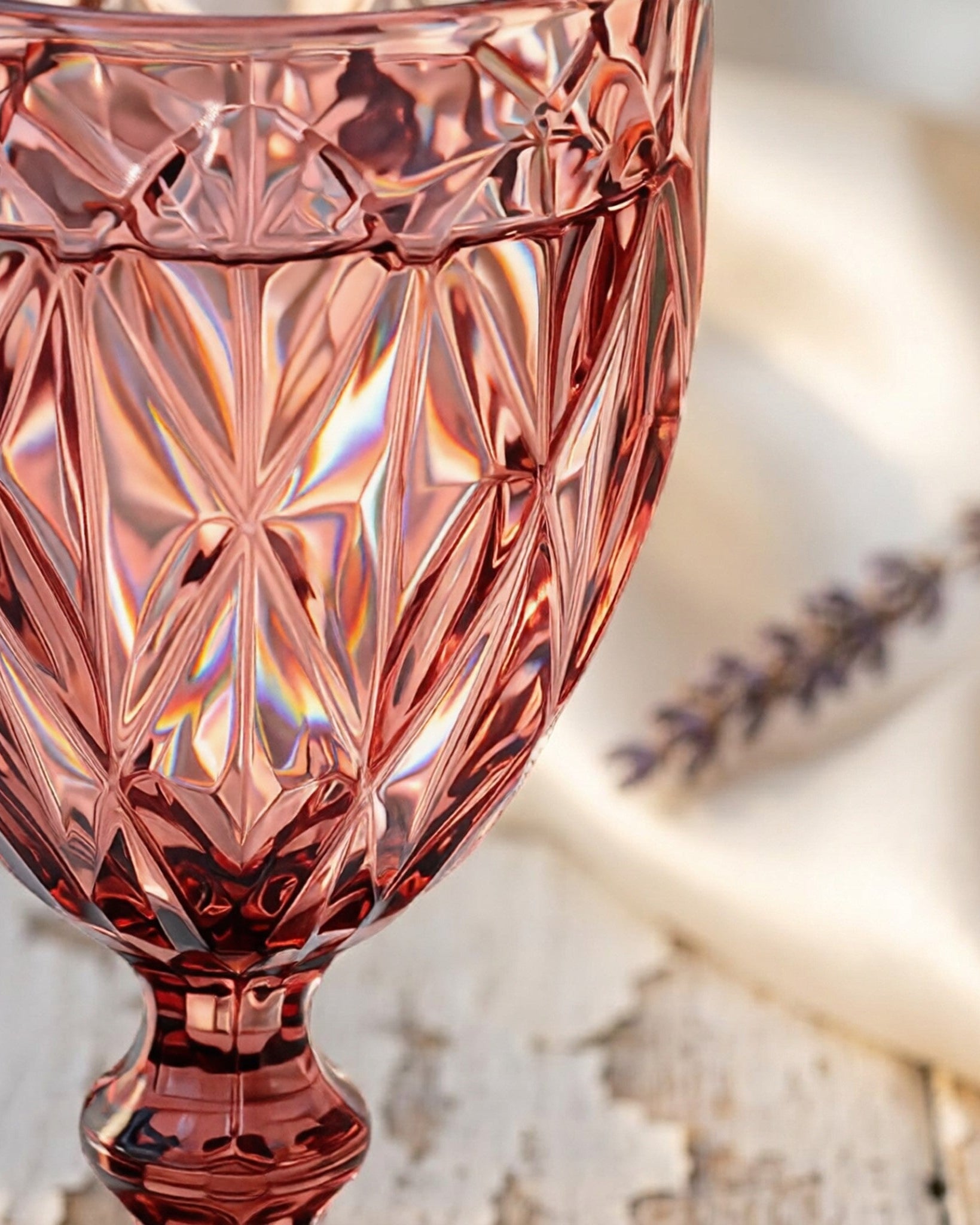 Set of pink glass goblets on a wooden surface with a white background