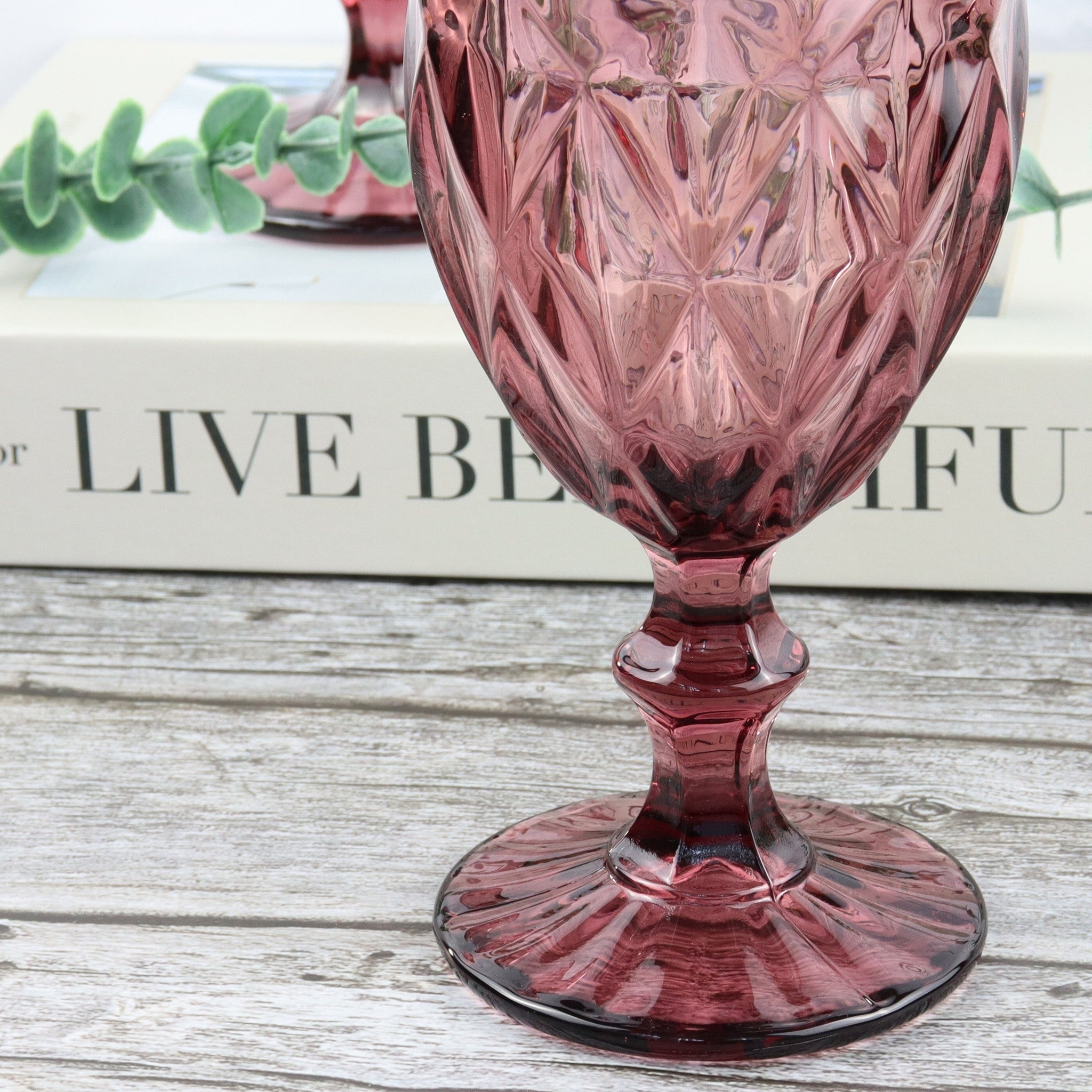 Set of pink glass goblets on a wooden surface