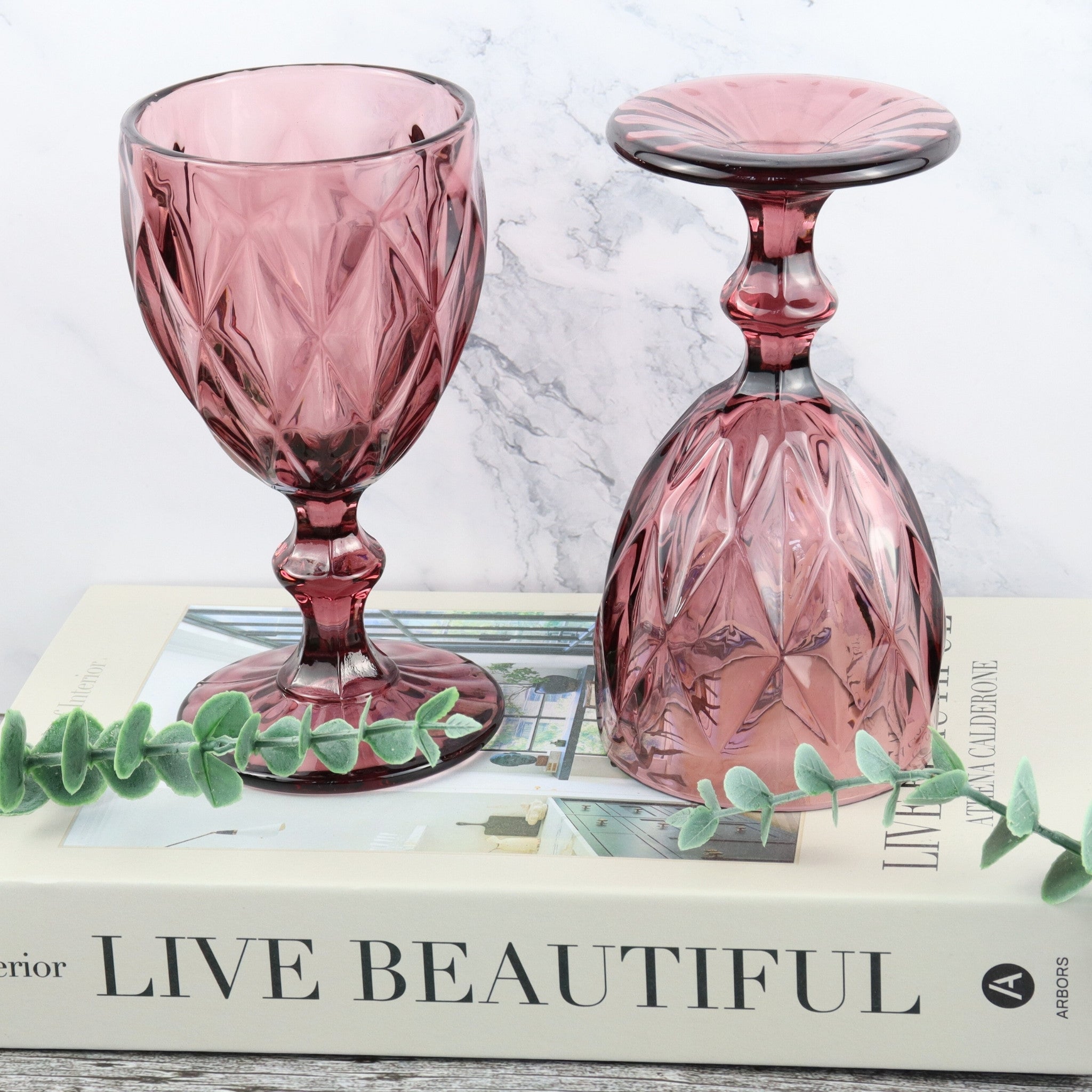 Set of pink glass goblets on a wooden surface