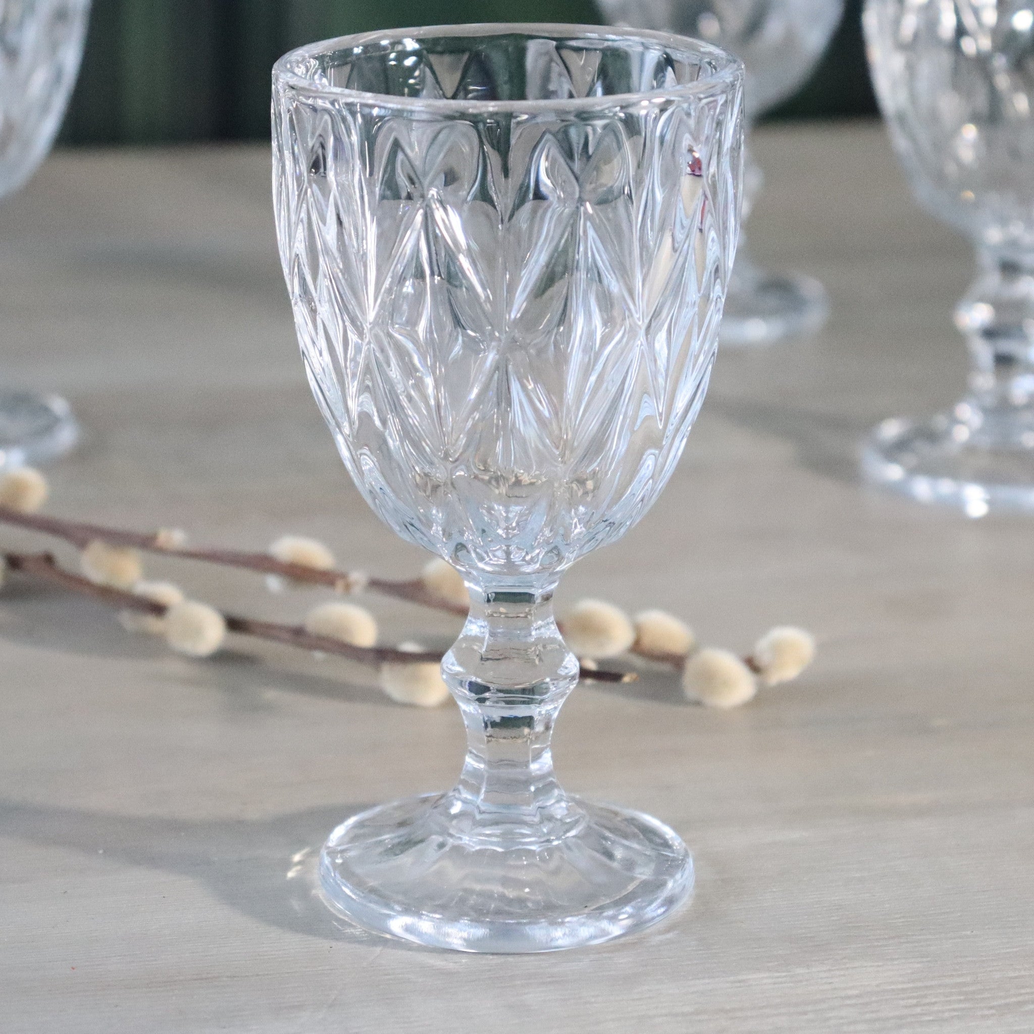 Clear wine glass with cut patterns on a wooden surface