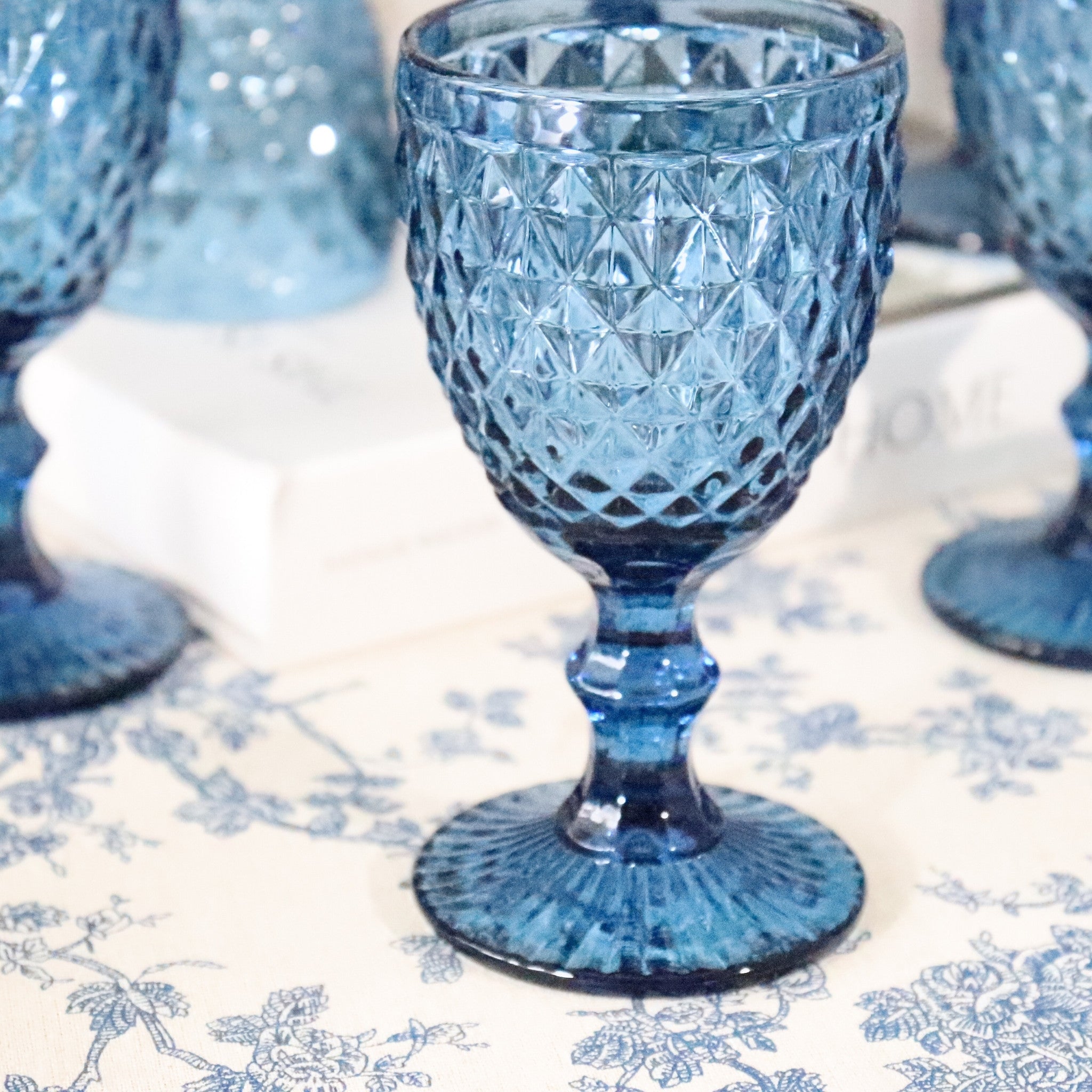 Blue textured glass goblet on a patterned tablecloth