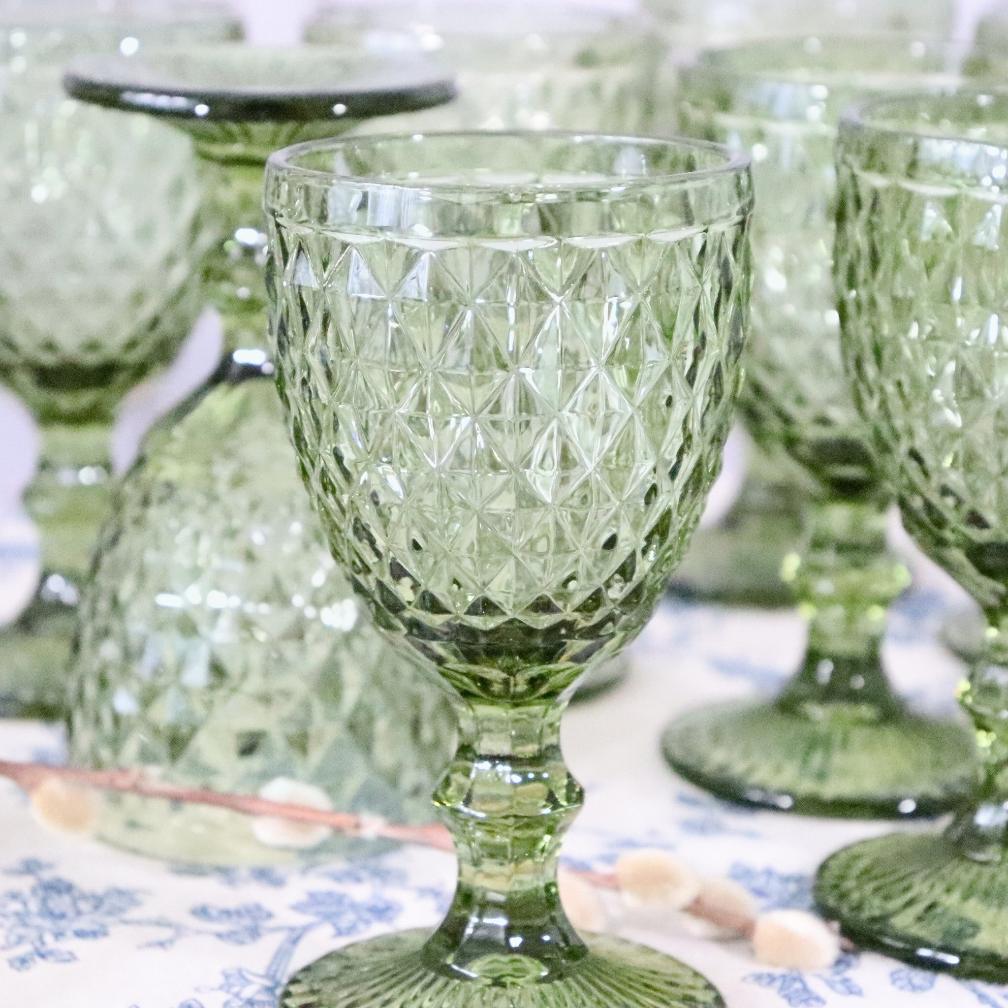Green textured glass goblets on a patterned surface