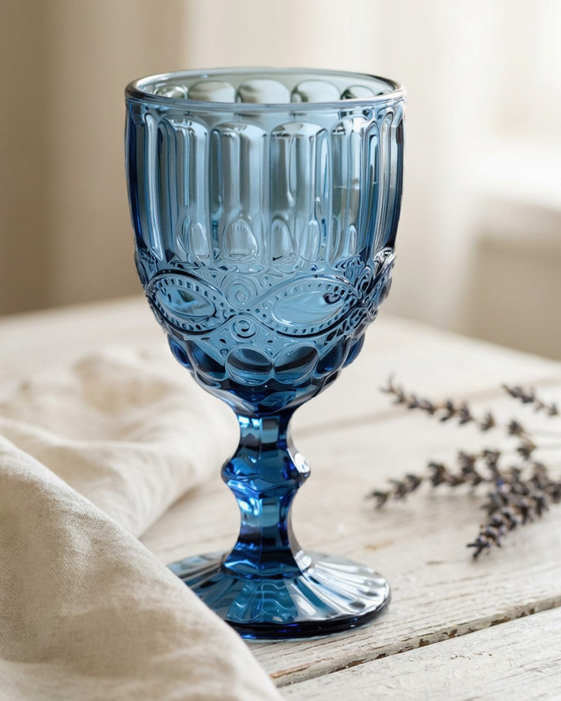 Blue glass goblet on a wooden surface with a blurred background