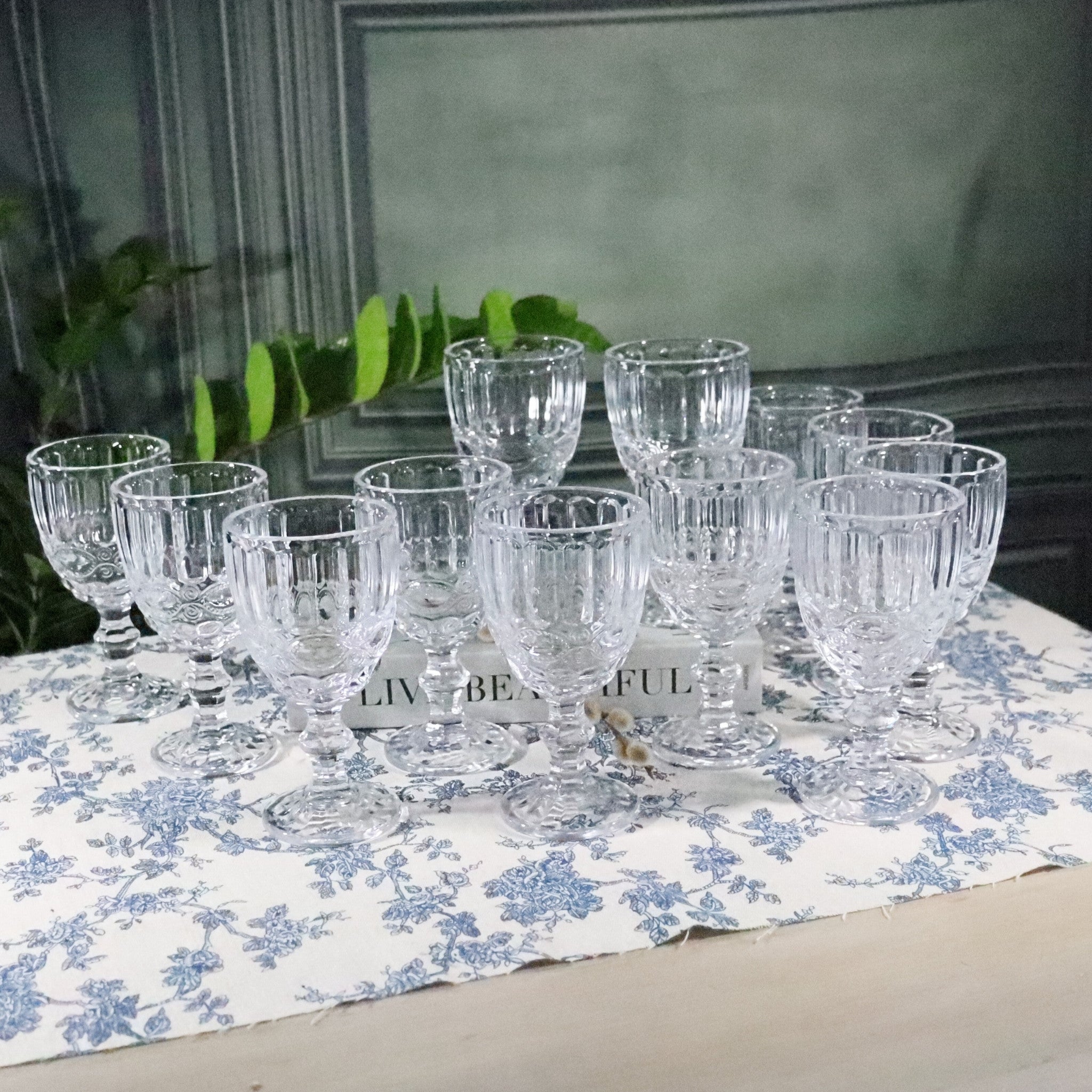 Set of clear glass goblets on a floral tablecloth with a blurred background