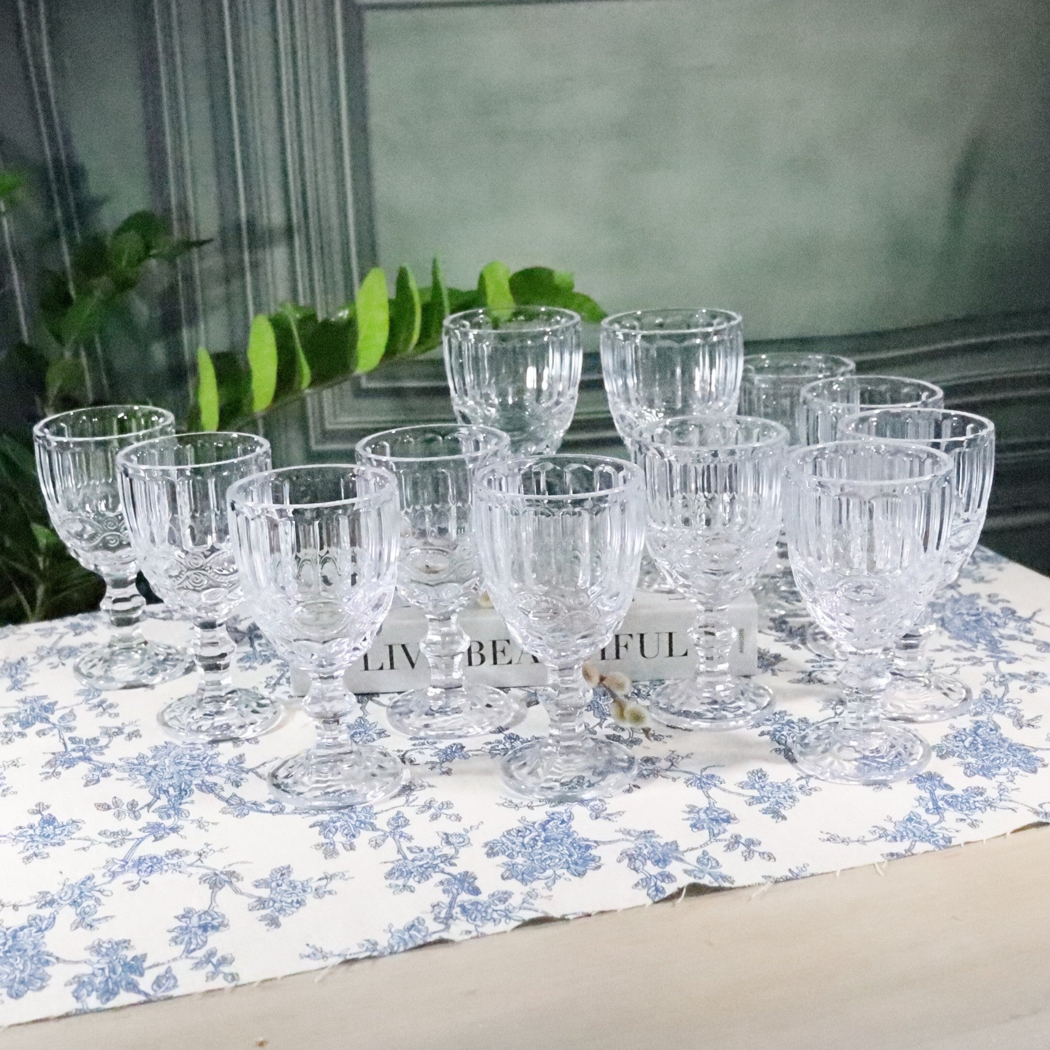 Set of clear glass goblets on a floral tablecloth with a blurred background