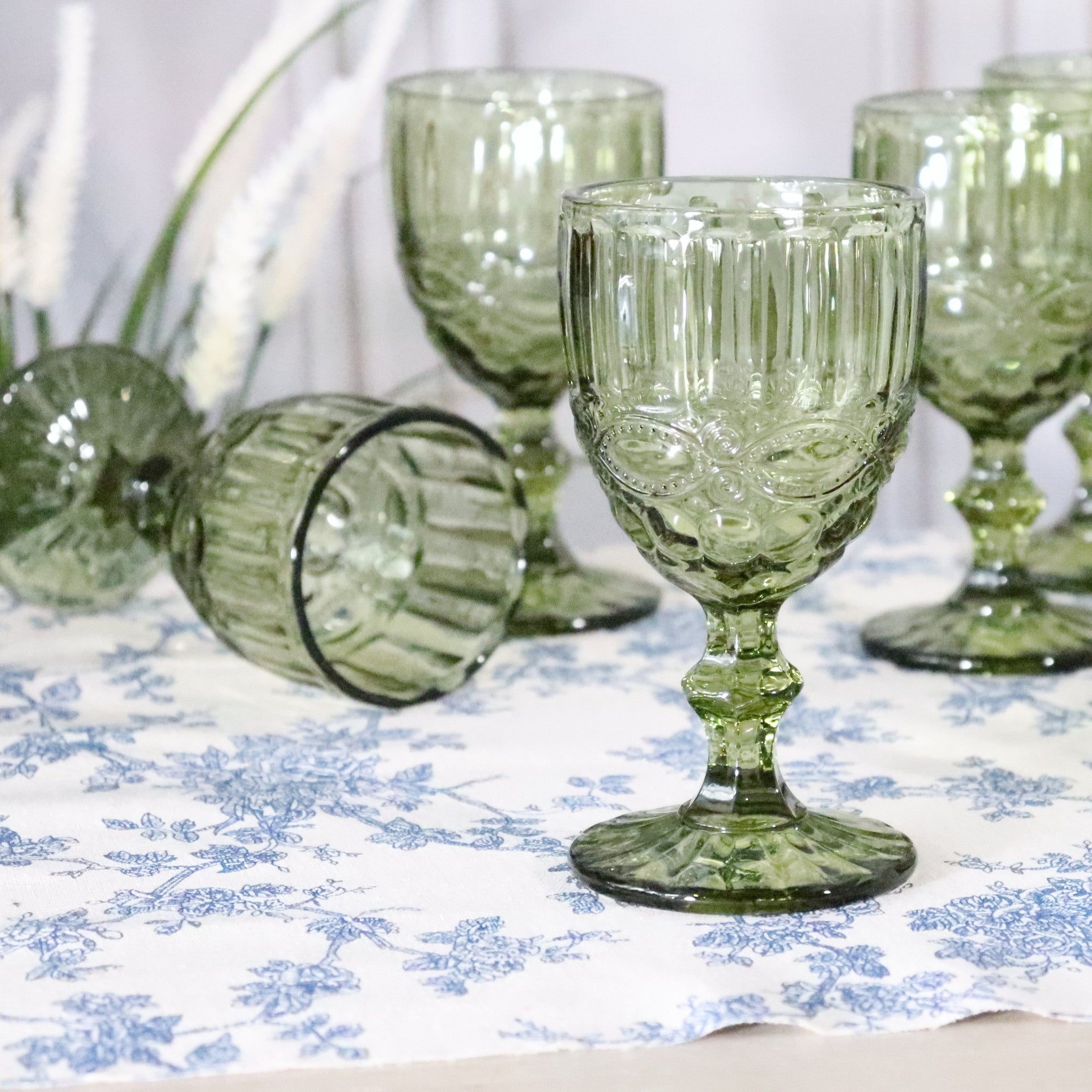 Green glass goblets on a patterned tablecloth