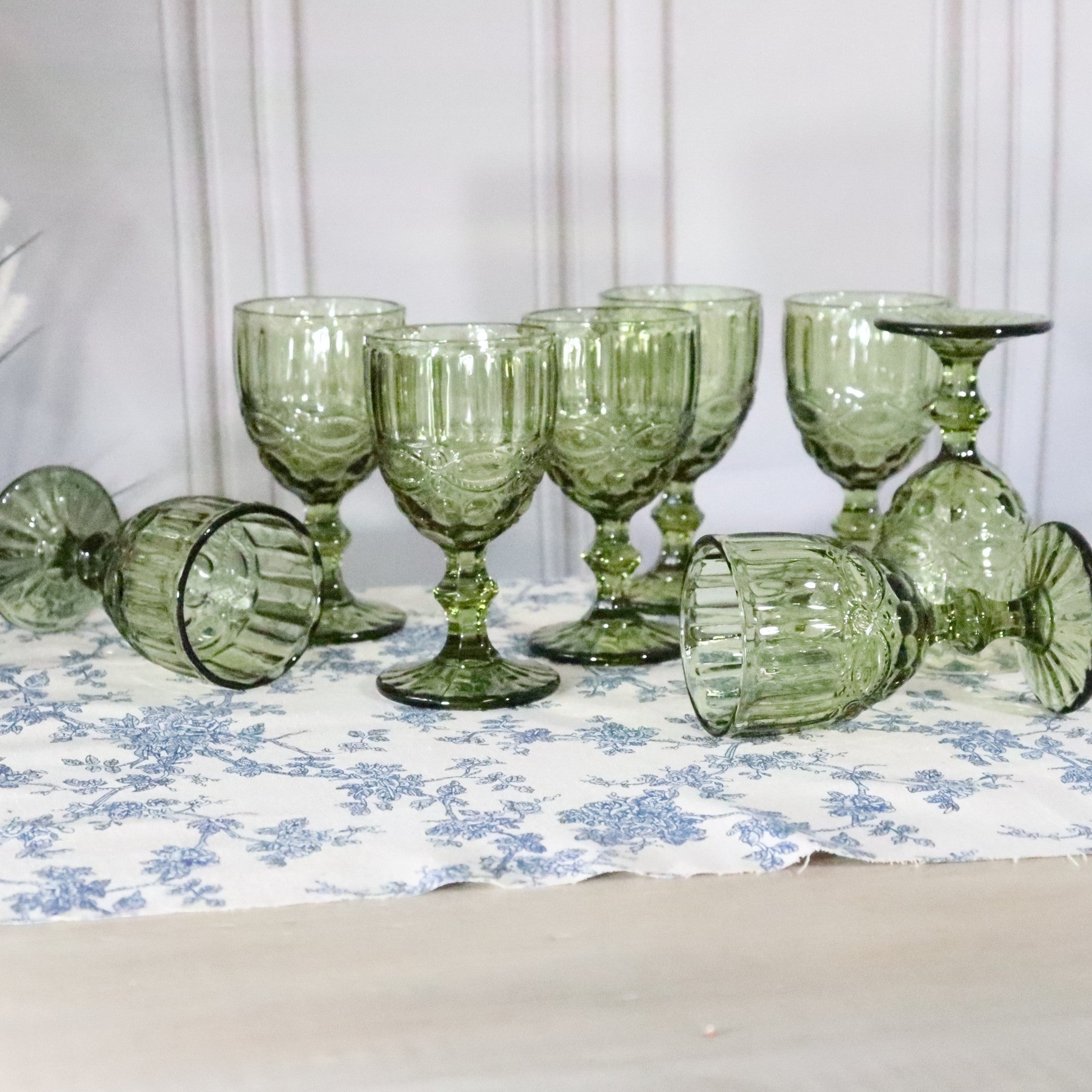 Set of green glass goblets on a floral tablecloth