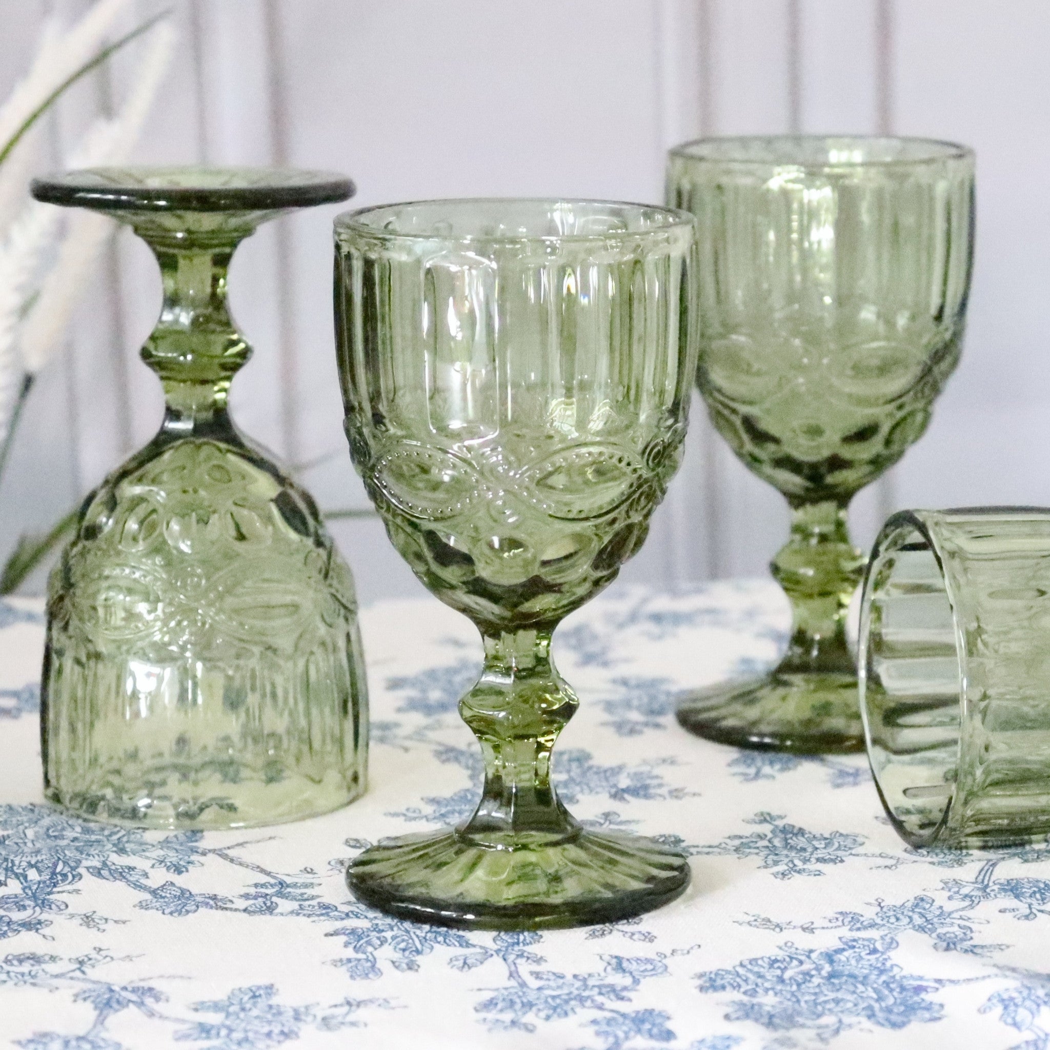 Set of green glass goblets on a floral tablecloth