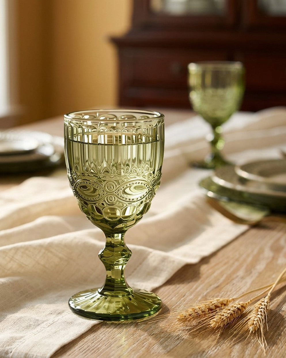 Green glass goblet on a wooden table with a soft focus background