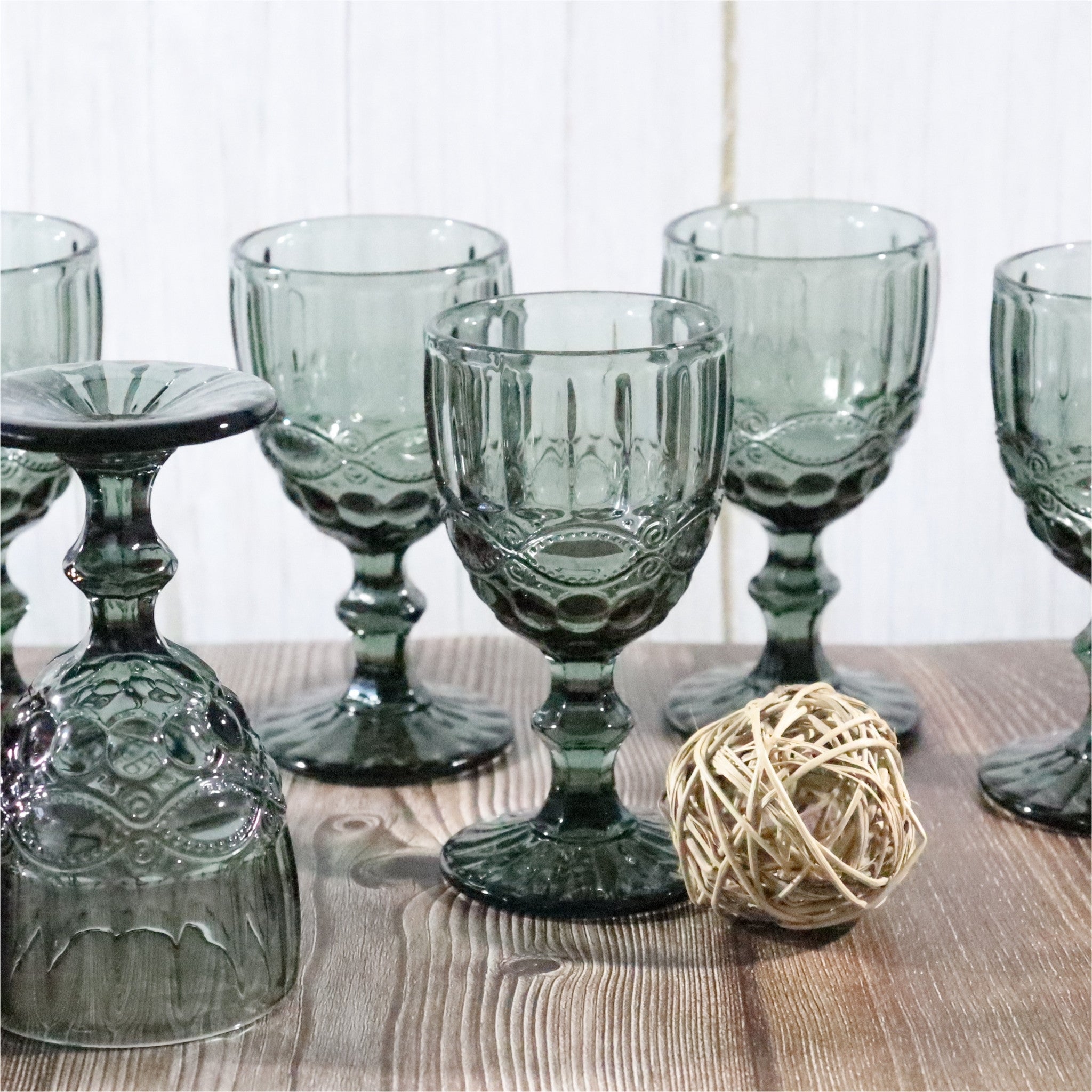 Set of grey glass goblets on a wooden surface with a decorative ball.