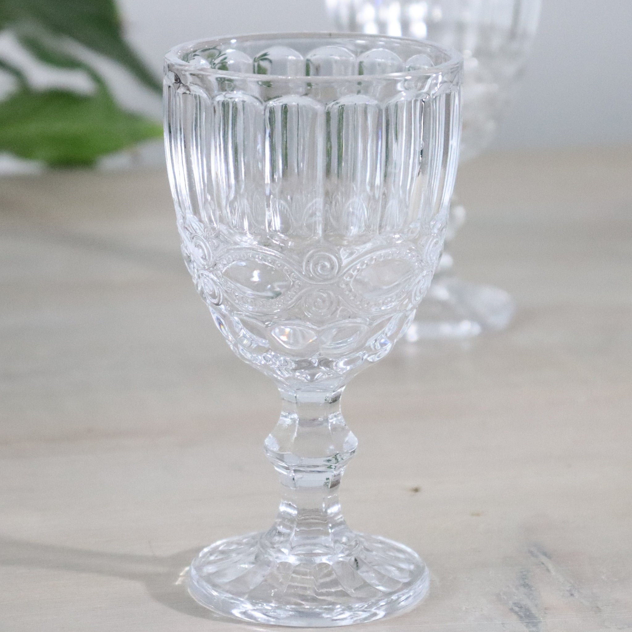 Clear glass goblets with intricate designs on a white surface