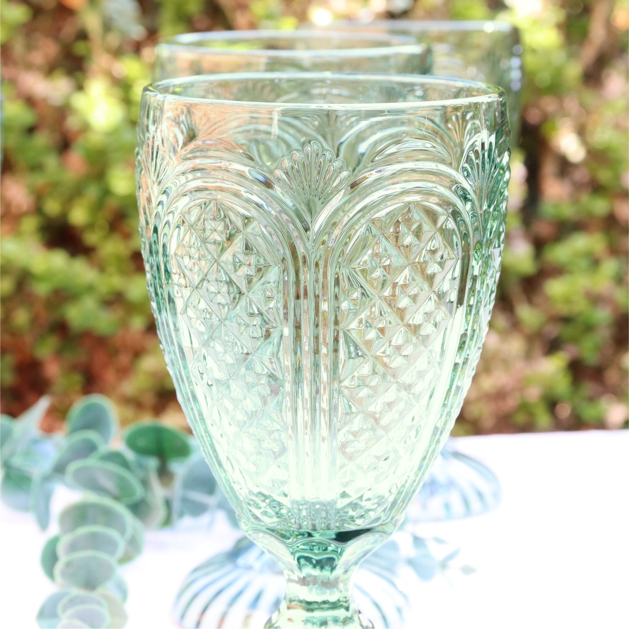 Green glass goblets with intricate patterns on a wooden surface