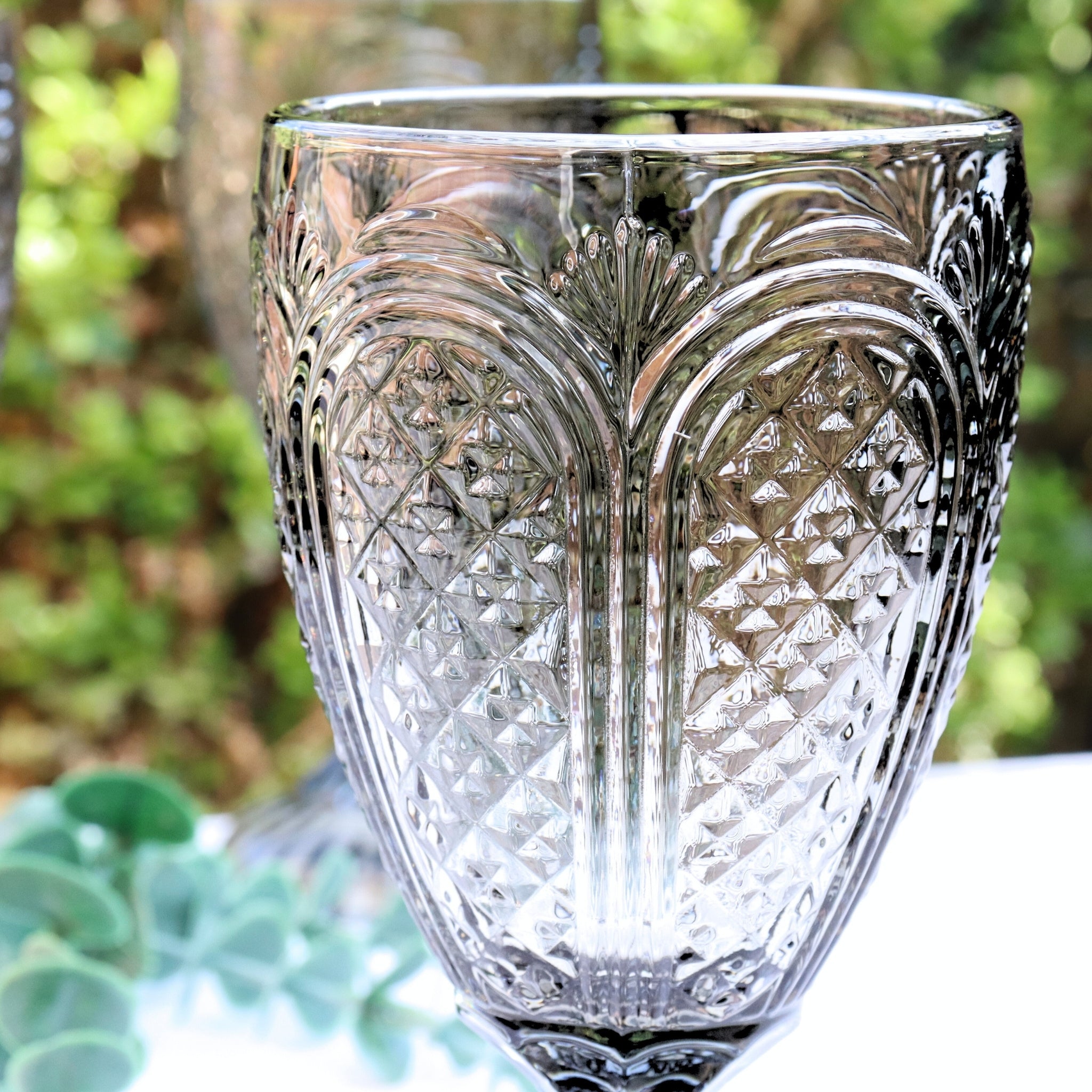 Grey glass goblets with intricate designs on a wooden surface.