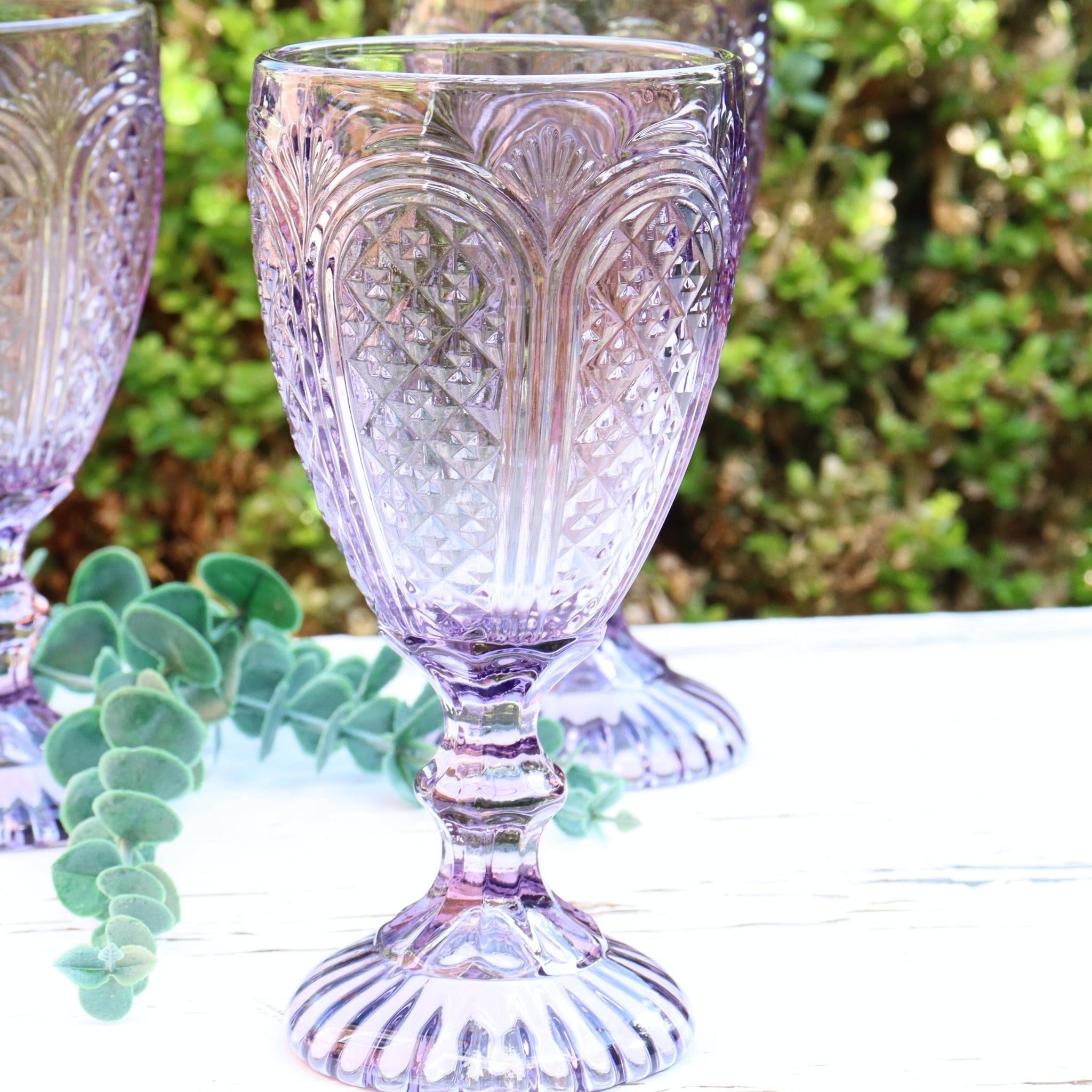 Decorative purple glass goblet on a blurred natural background