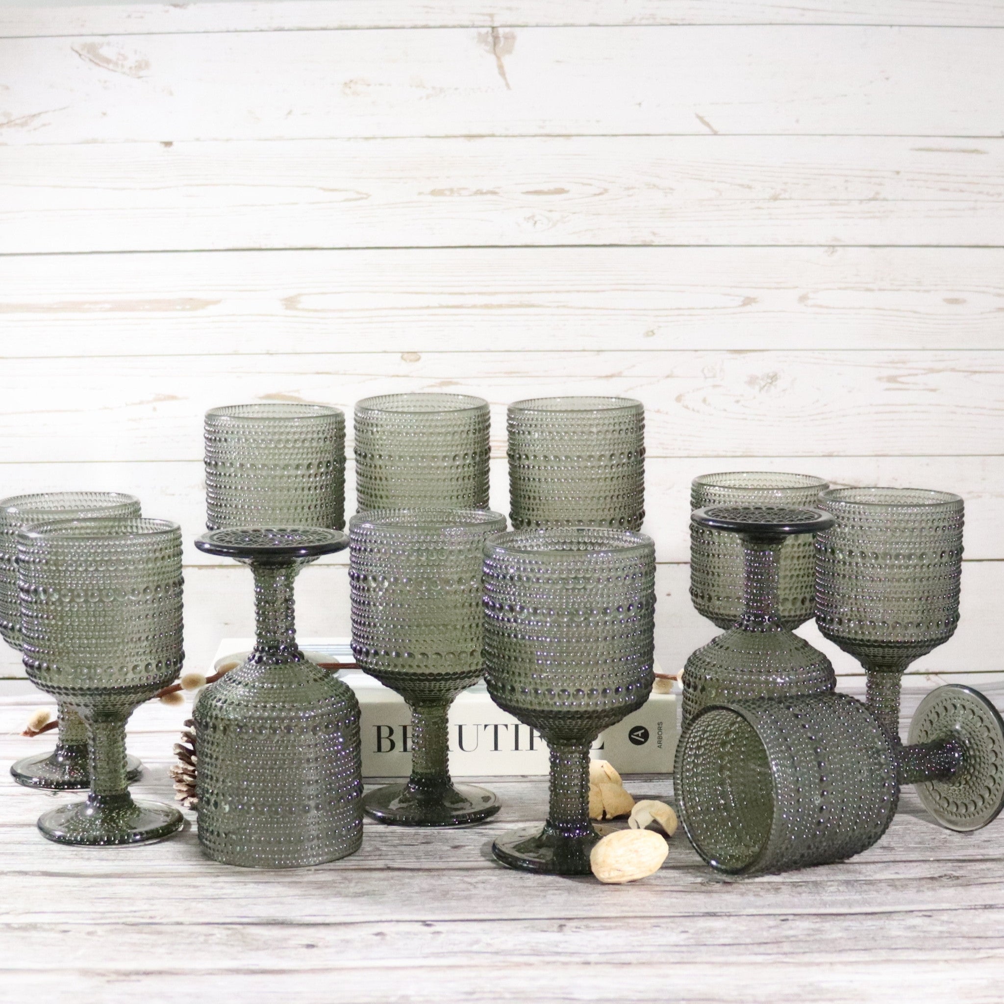 Set of green textured glassware on a wooden surface with a light wood panel background