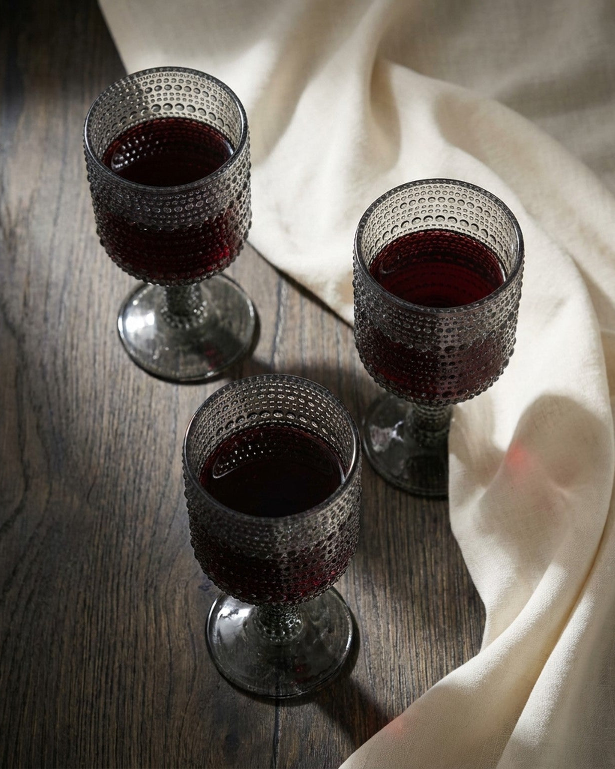 Set of textured gray glass goblets on a wooden surface with decorative elements.