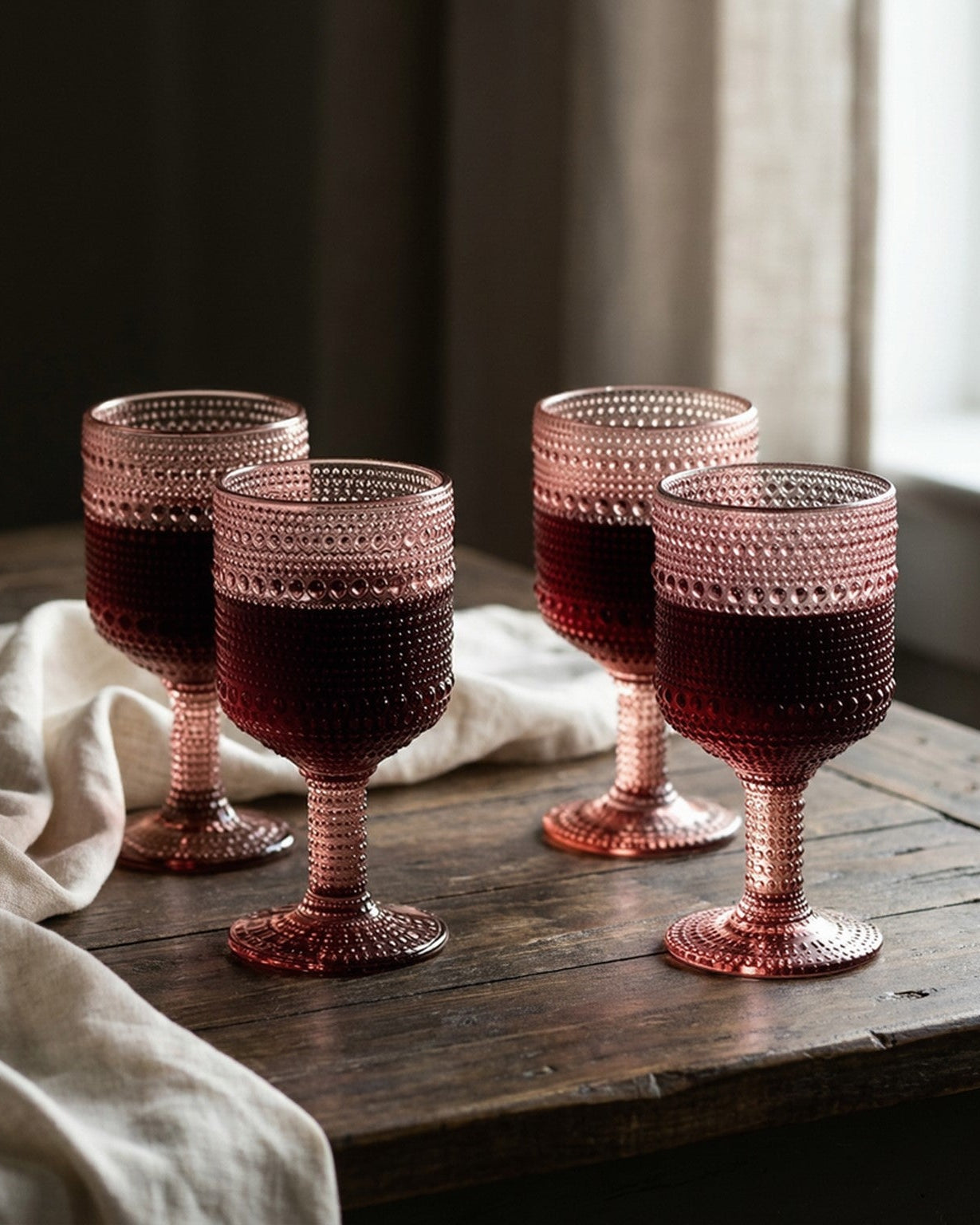 Set of four purple beaded glasses on a decorative table with 'This is Home' sign.