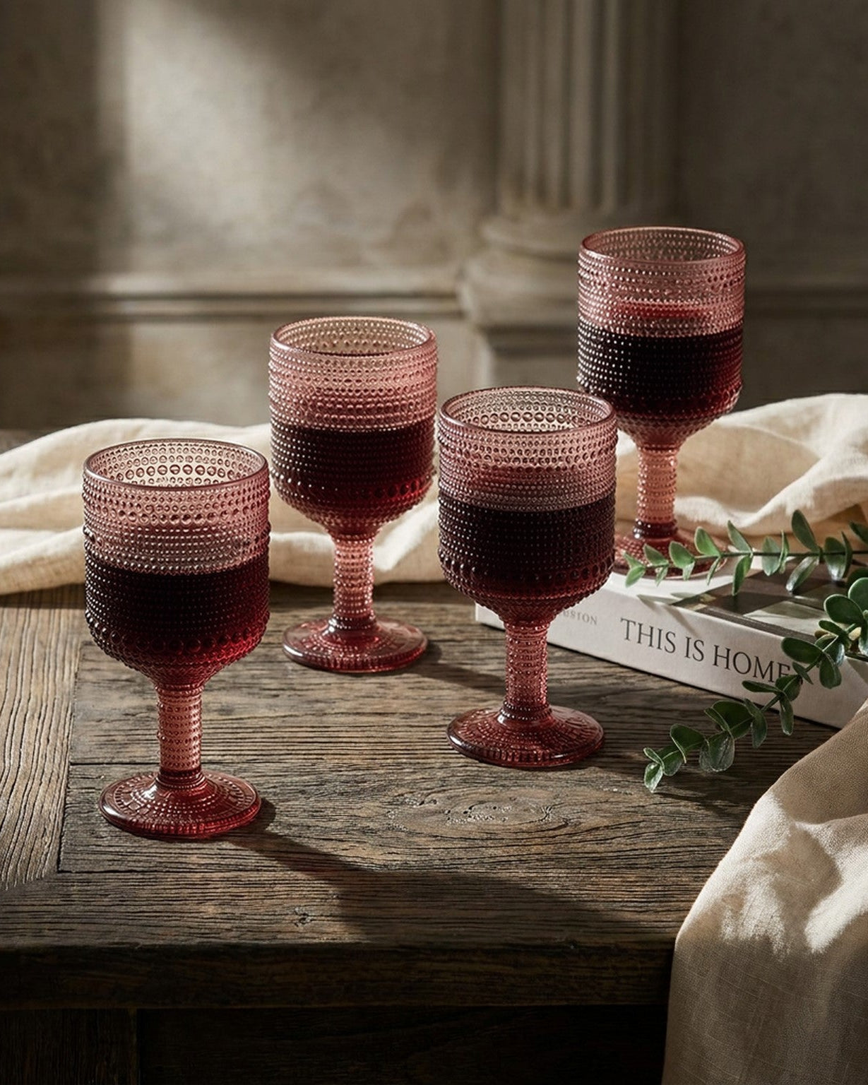 Set of four purple beaded glasses on a decorative tablecloth with greenery.