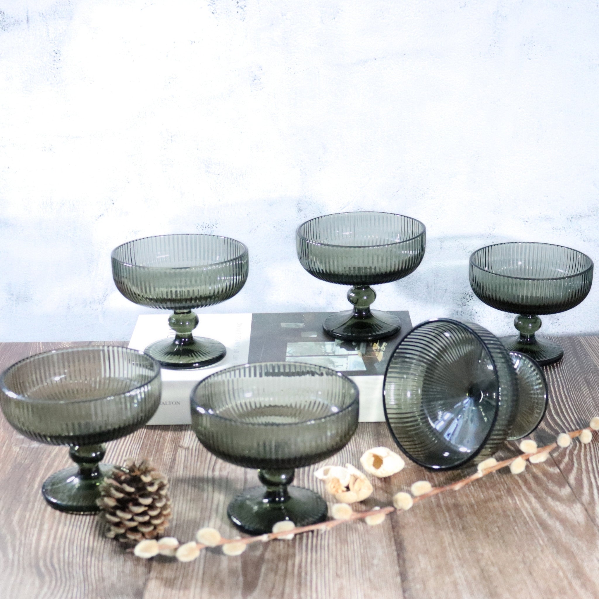 Set of smoked glass dessert bowls on a wooden surface with decorative elements.