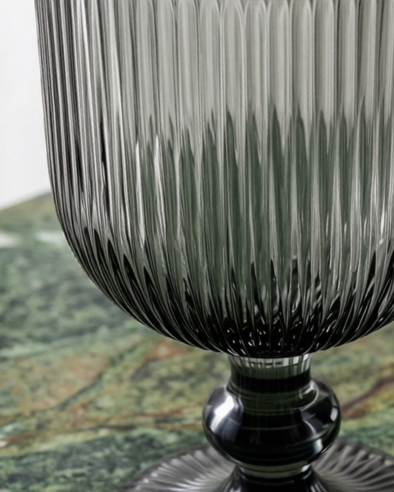 Set of ribbed glass goblets on a wooden surface with a pine cone.