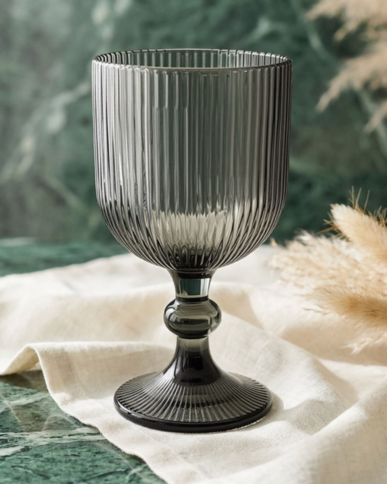 Set of ribbed glass goblets on a wooden surface with decorative elements.