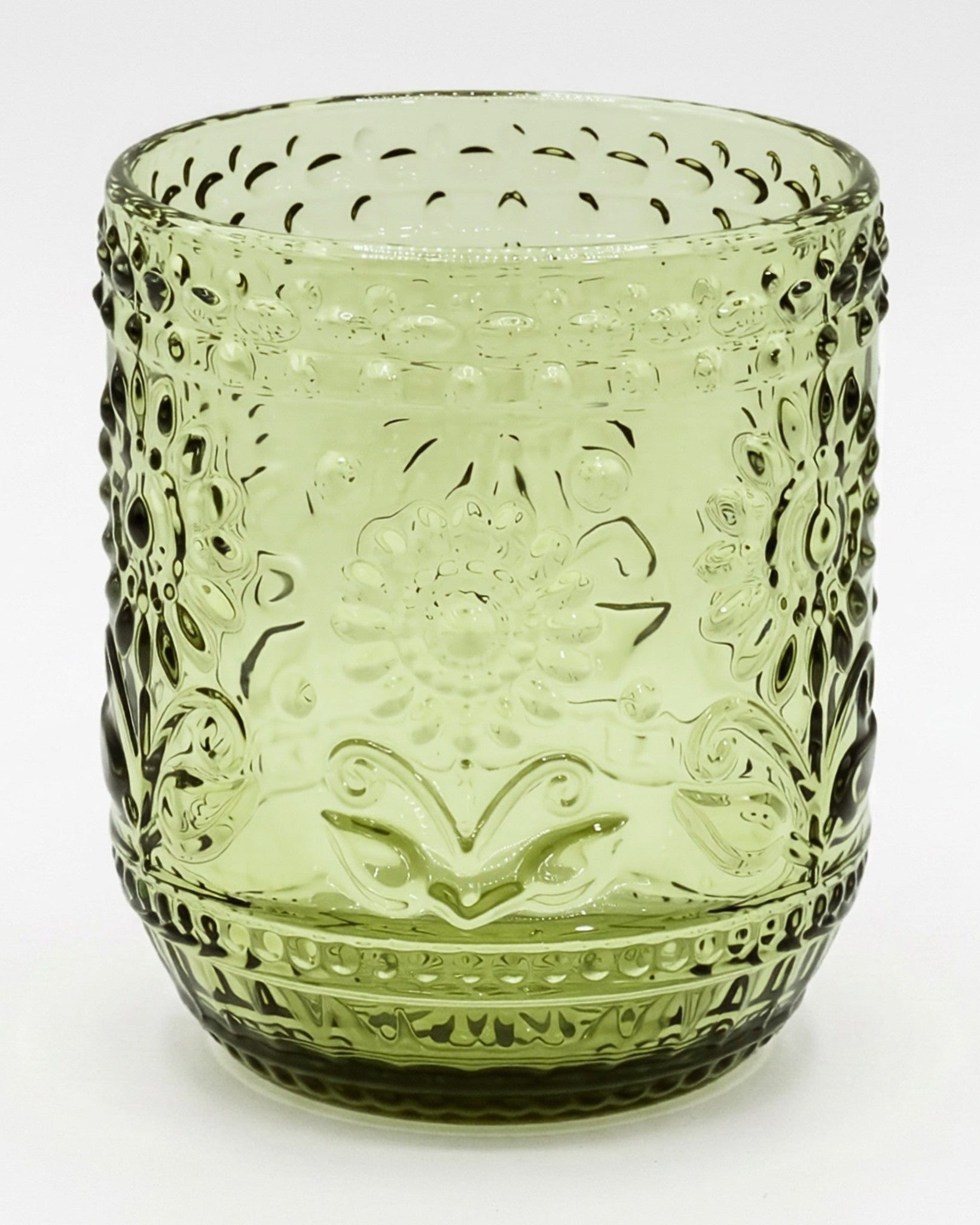 Green glass tumbler with decorative patterns on a white background