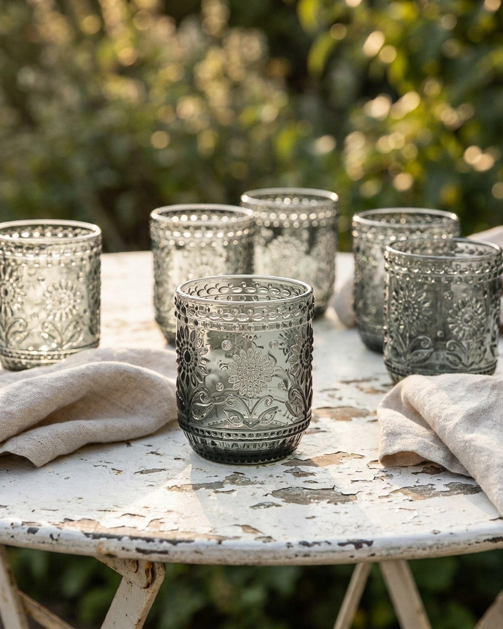 Decorative glass tumblers on a rustic table outdoors