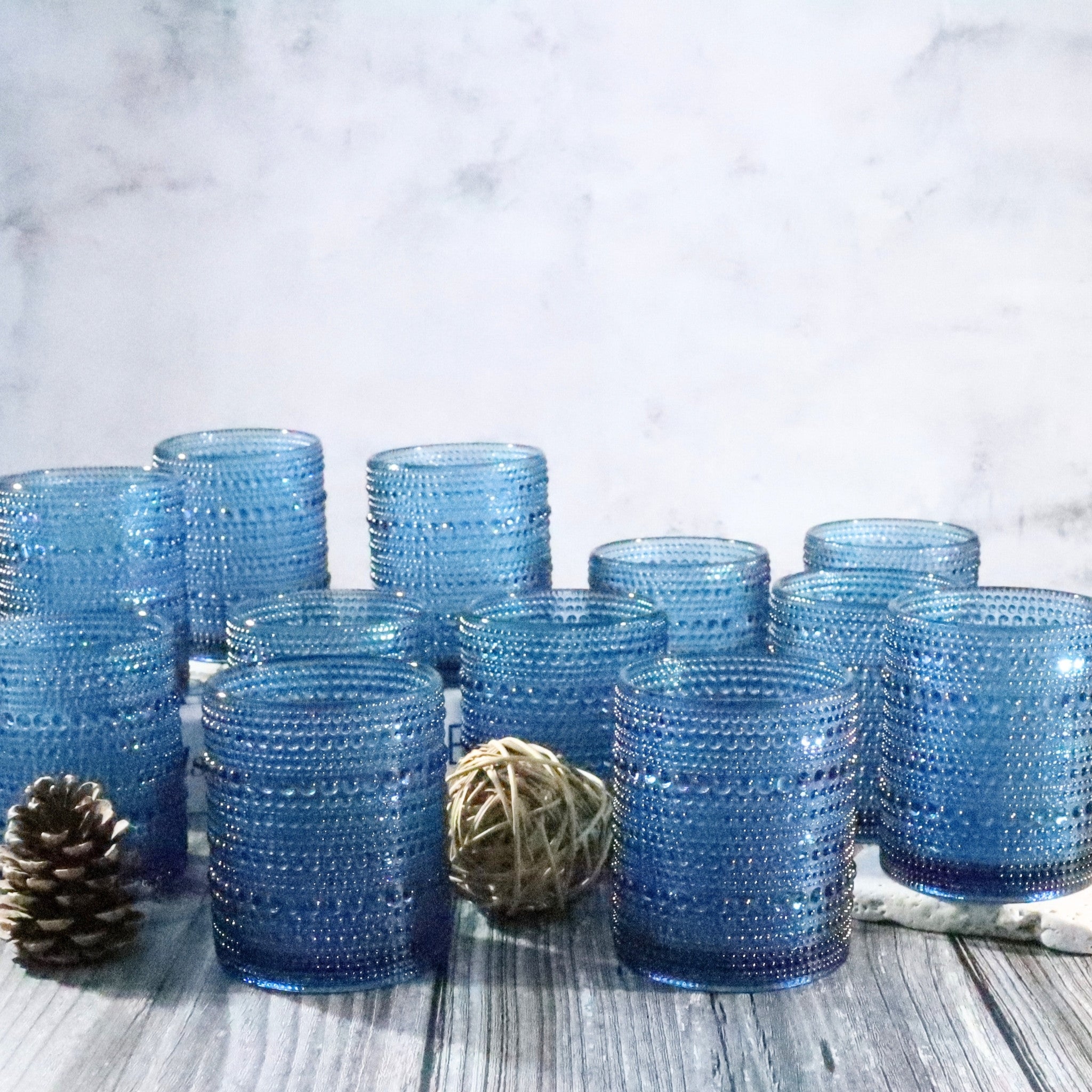 Set of Blue hobnail beaded glass rocks tumblers on a wooden surface with a light gray background