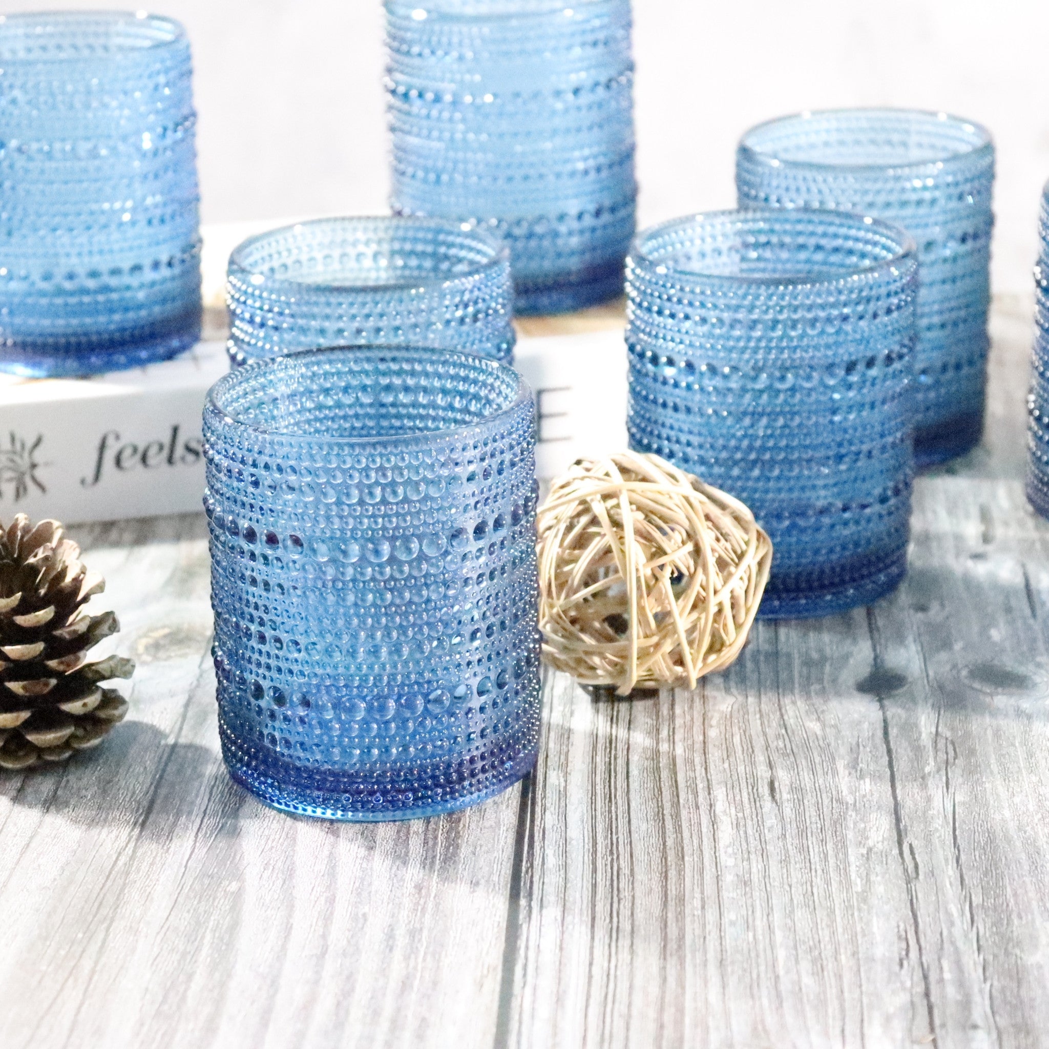 Set of blue Blue hobnail beaded glass rocks tumblers on a wooden surface with decorative elements.
