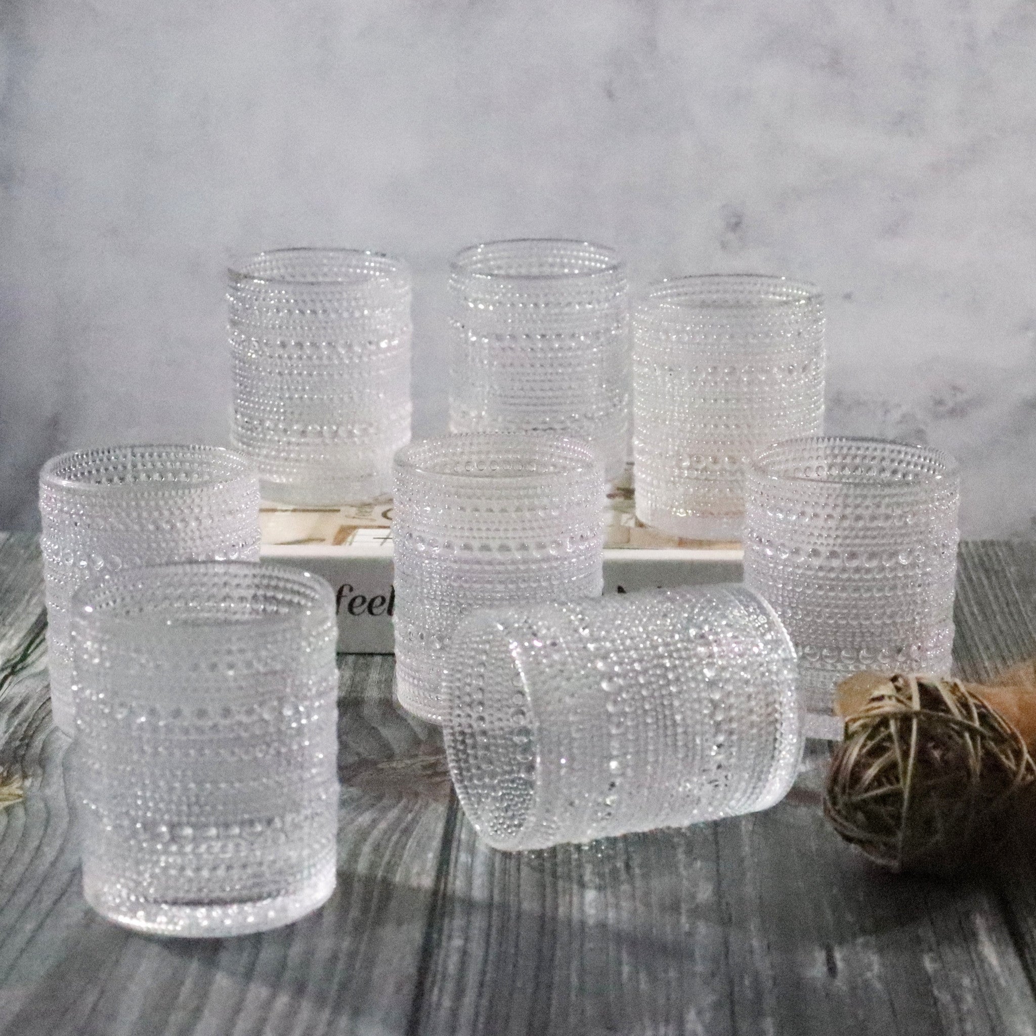 Set of clear textured glass tumblers on a wooden surface with a neutral background