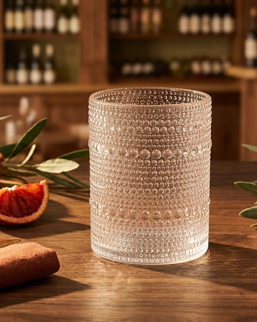 Set of 12 clear hobnail glass tumblers on a wooden surface with a marble background