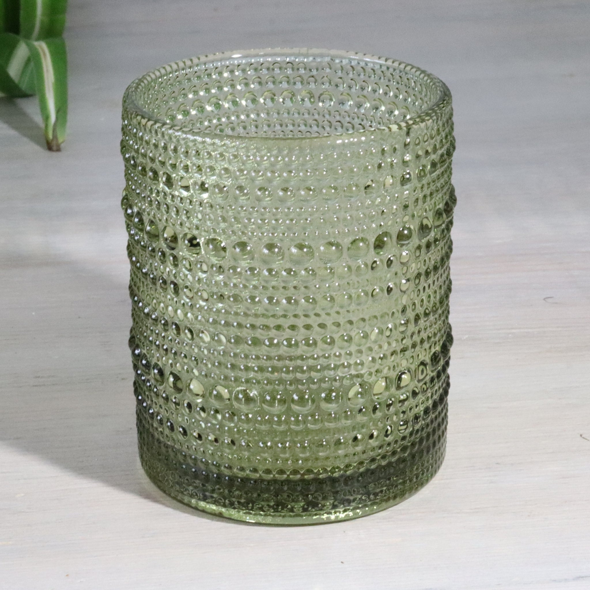 Green hobnail glass tumblers on a white surface