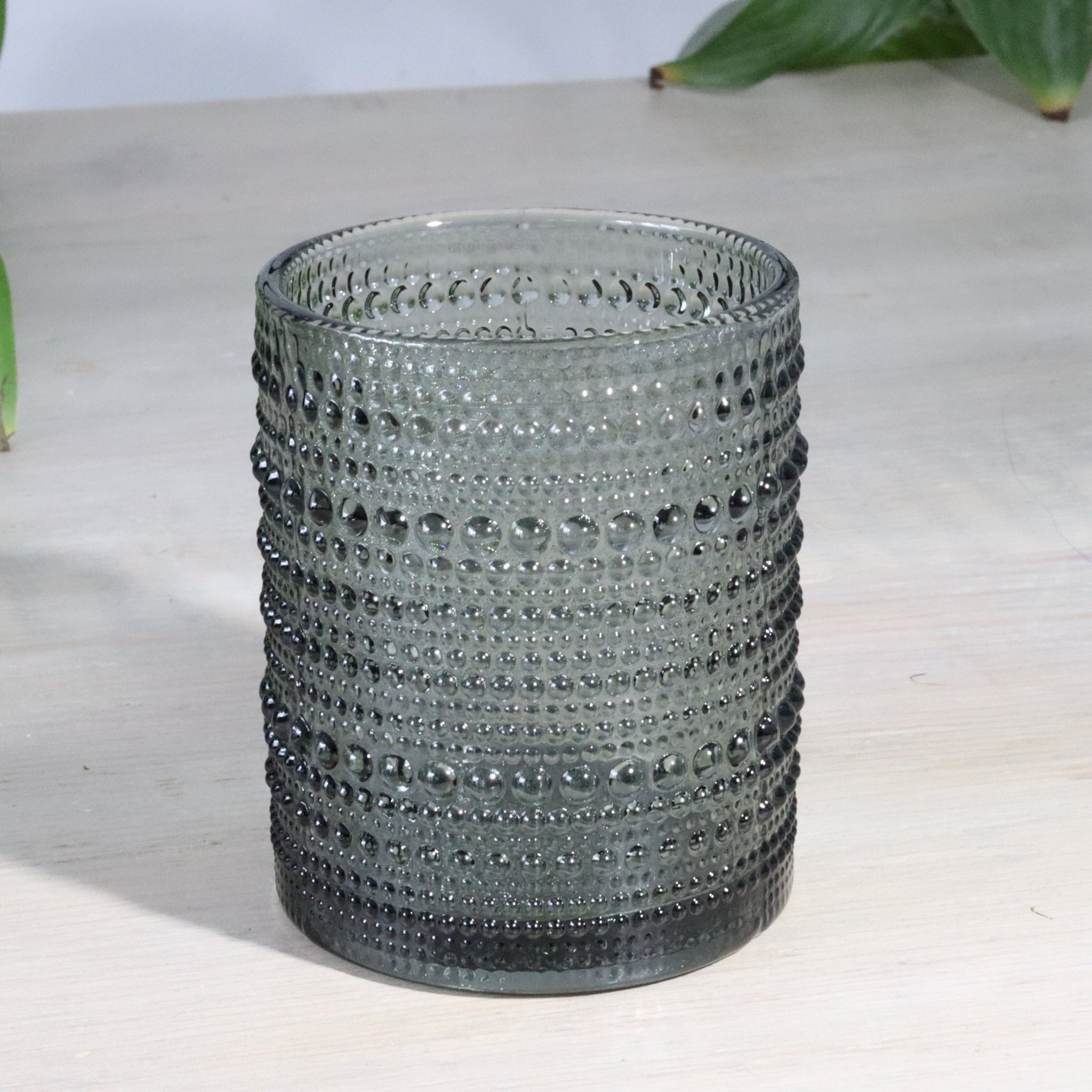 hobnail glass tumbler with a textured pattern on a white surface.