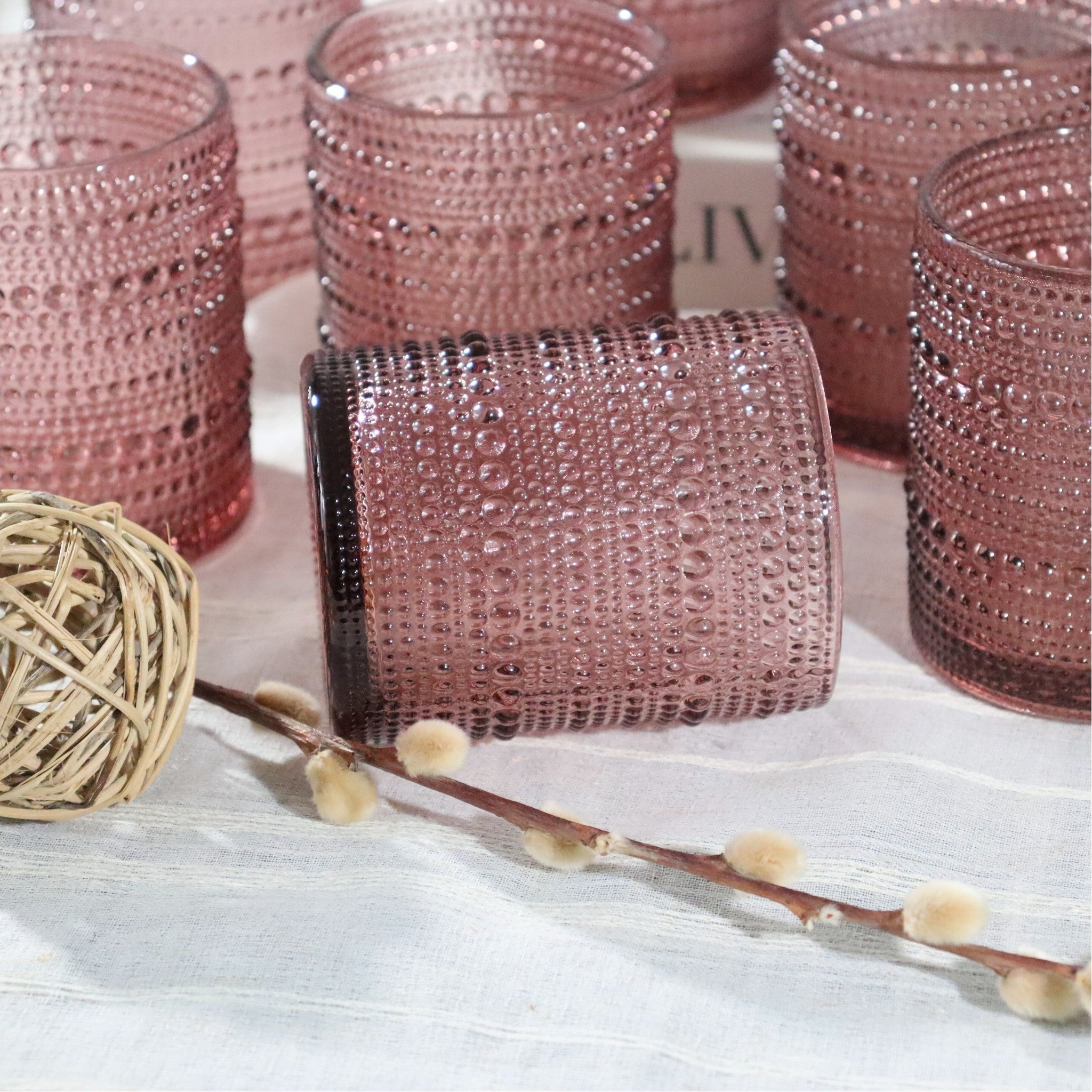 Purple textured glass tumbler on a white surface with decorative elements.