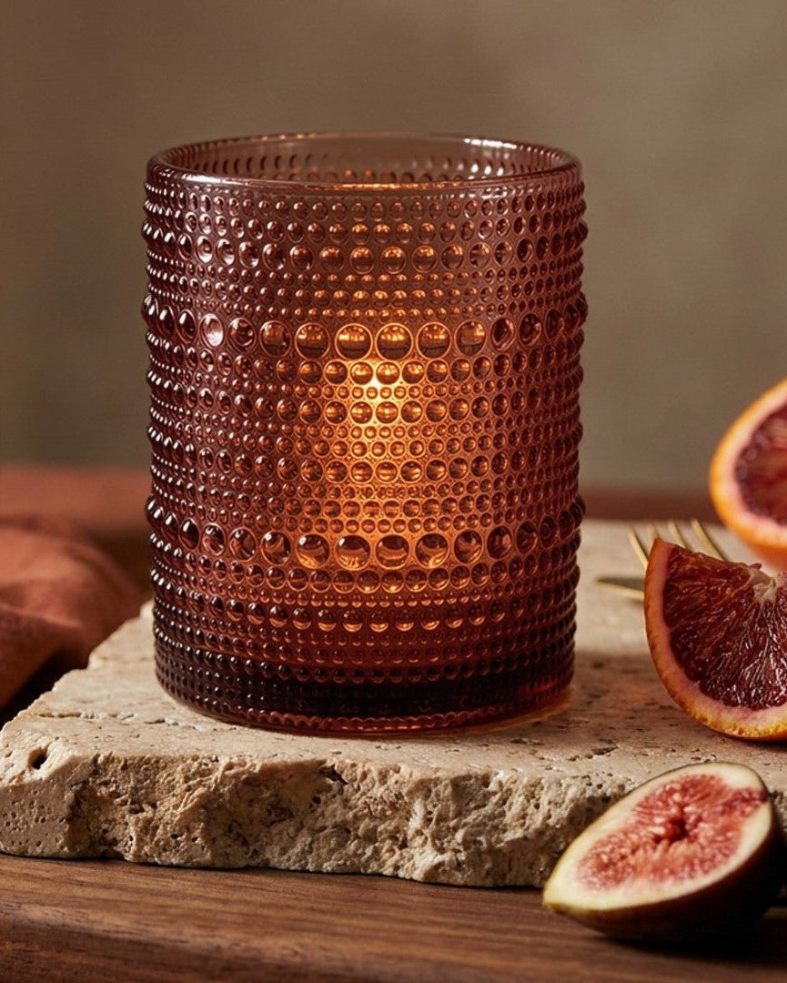 Purple textured glass tumbler on a white surface with decorative elements.
