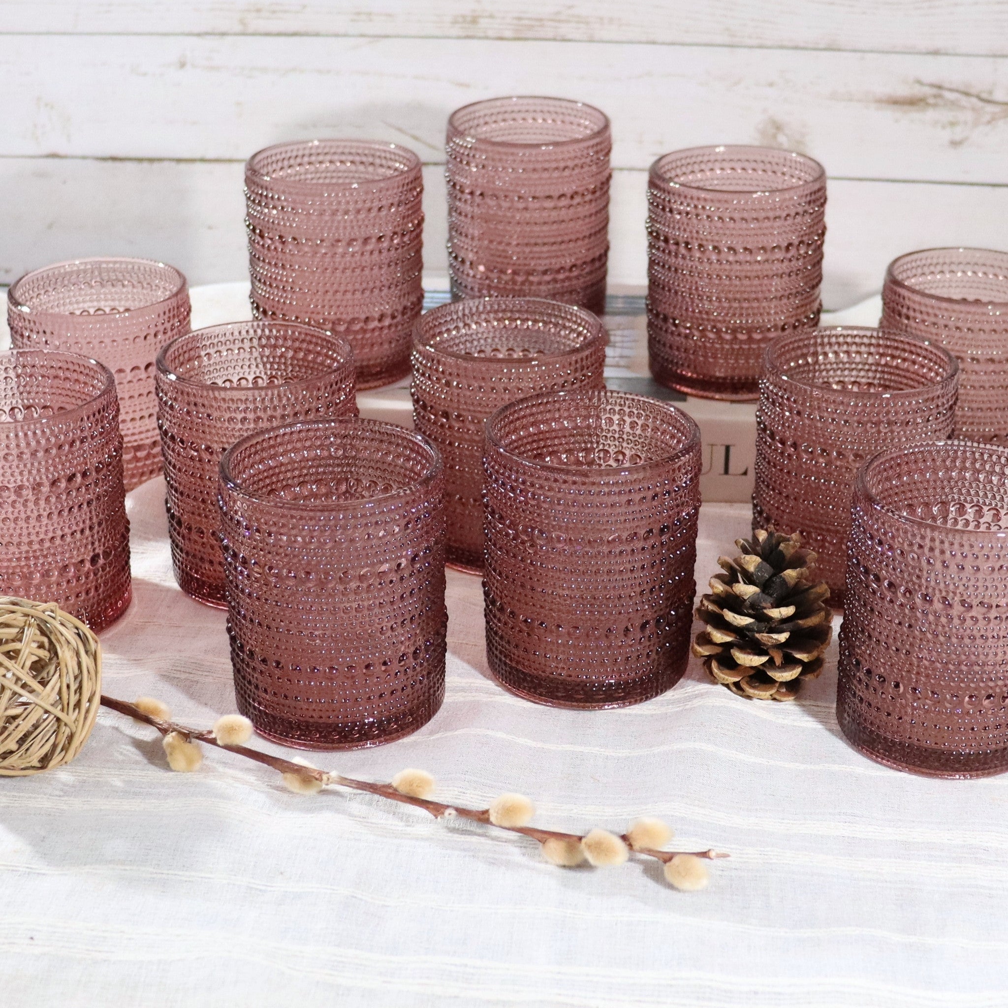 Set of purple textured glass tumblers on a white surface with decorative elements.