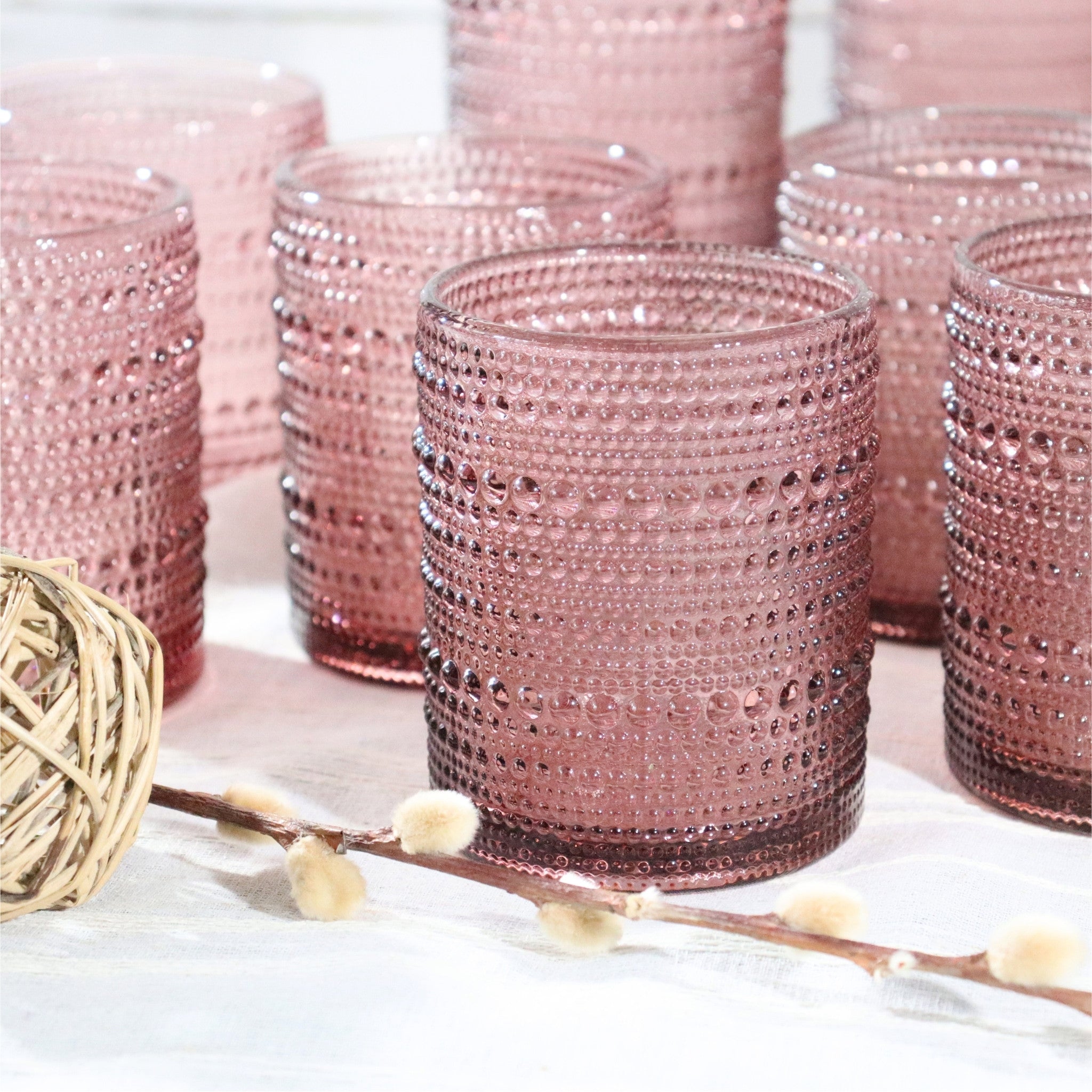Set of purple textured glass tumblers on a white surface with decorative elements.