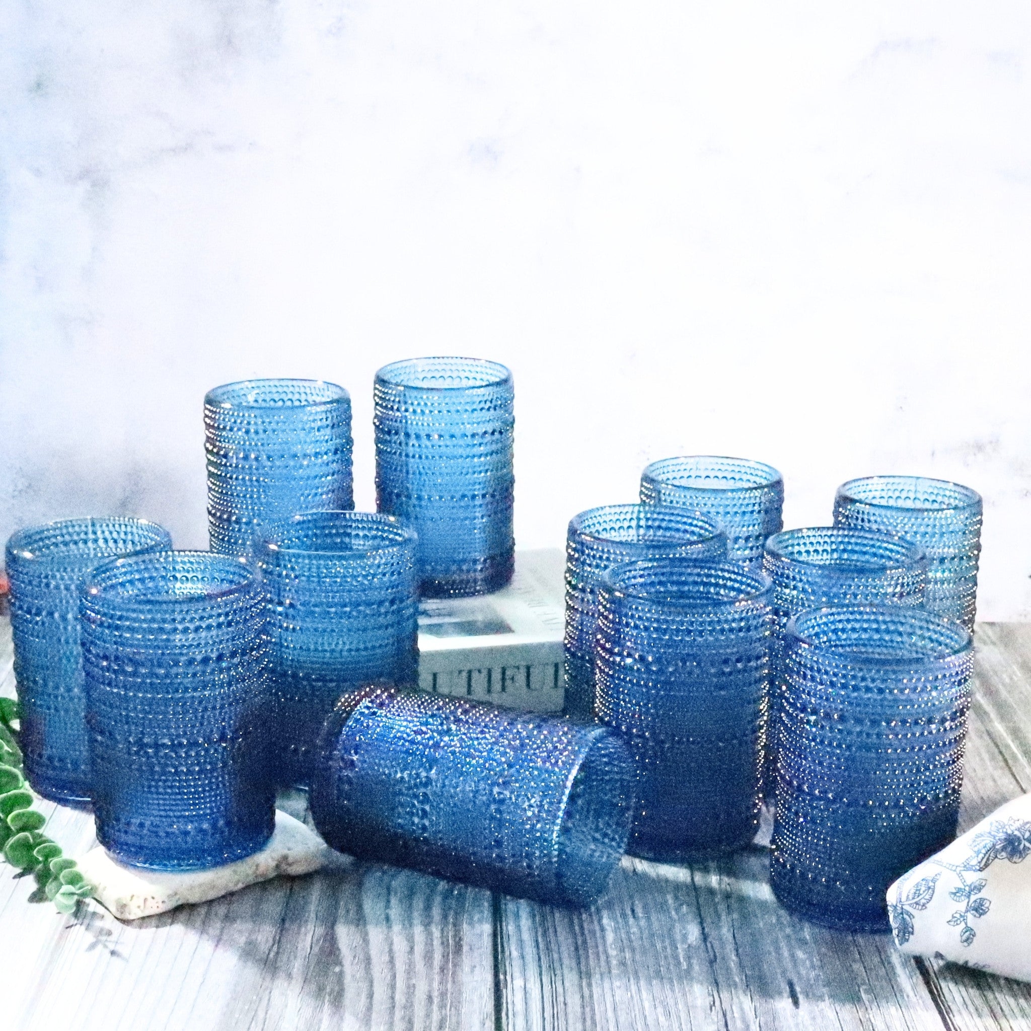 Set of blue textured glass tumblers on a white surface with a blurred background