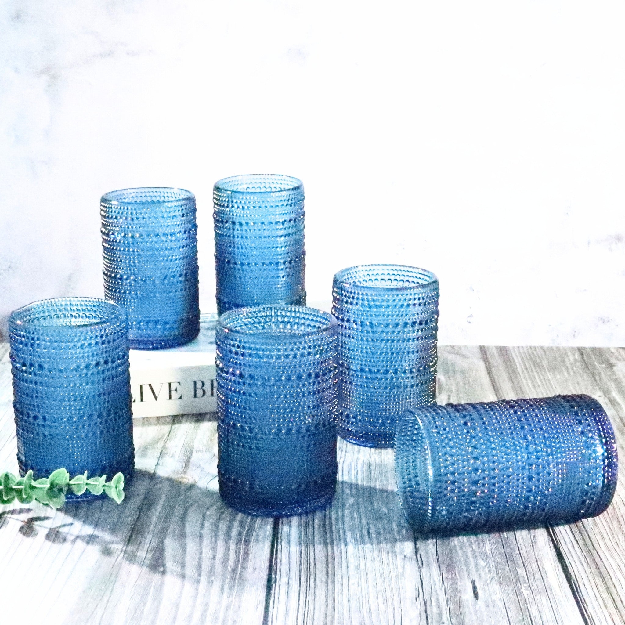 Set of blue textured glass tumblers on a wooden surface with a white background