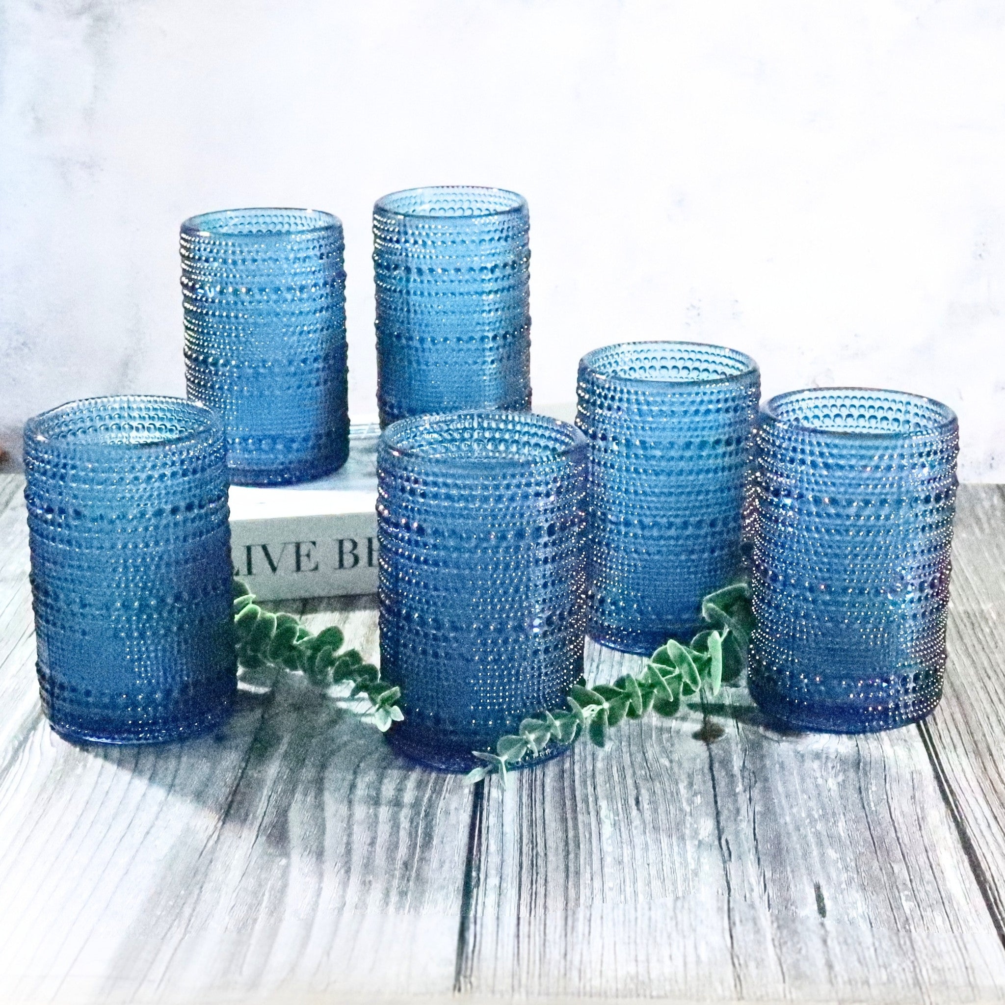 Set of blue textured glass tumblers on a wooden surface with a white background