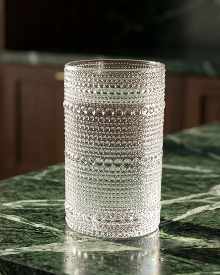 Set of clear textured glass tumblers on a wooden surface with a marble background