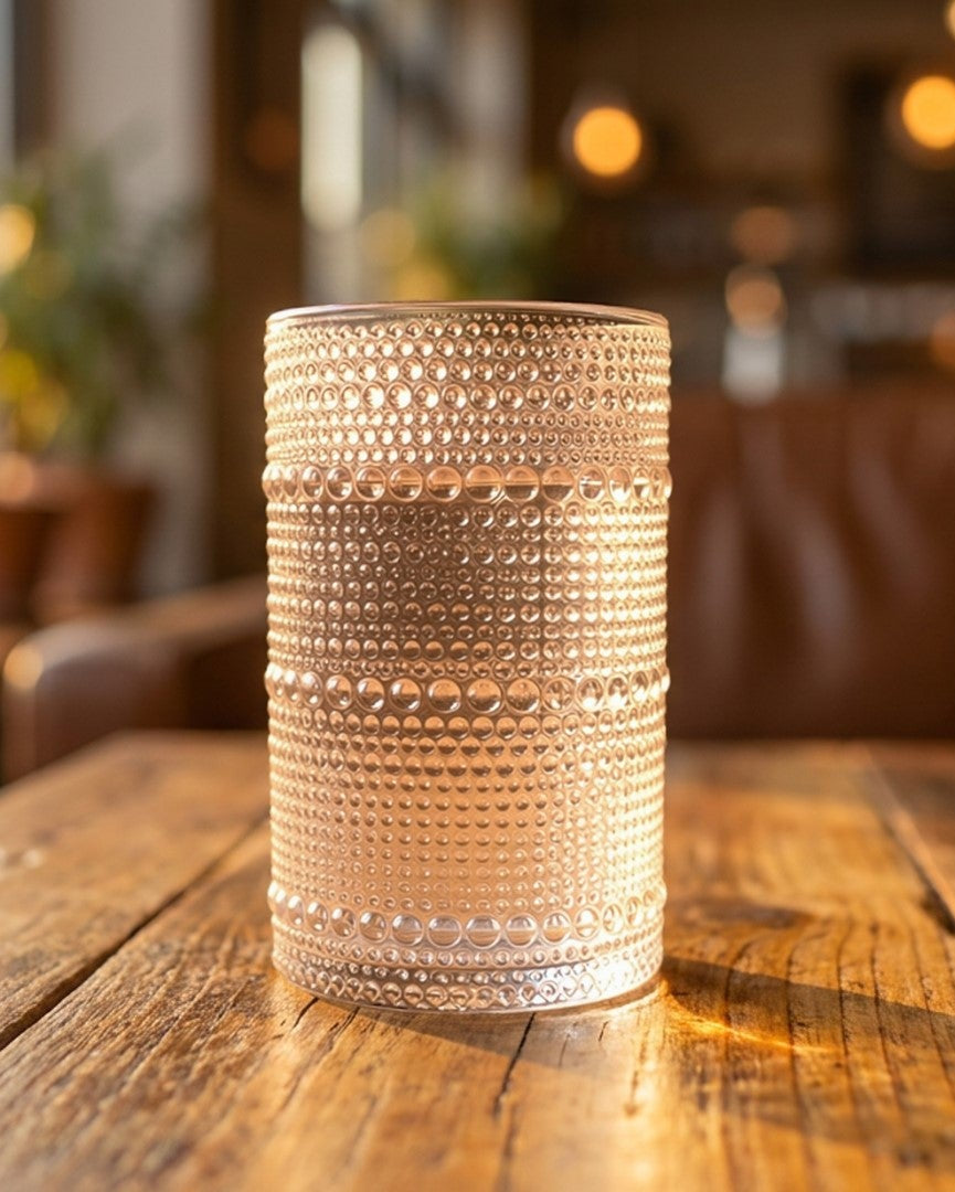 Set of textured glass tumblers on a wooden surface with a marble wall background