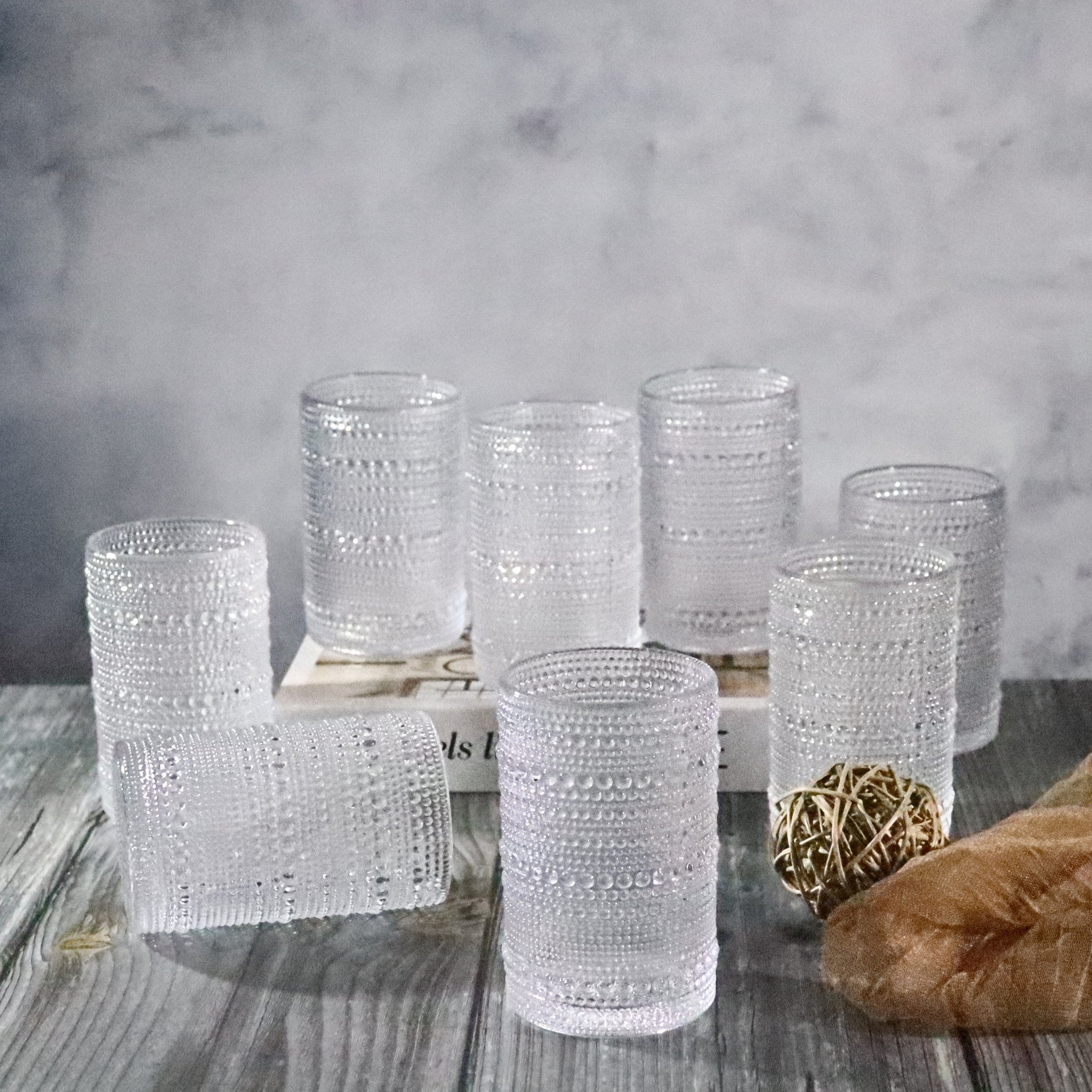 Set of textured glass tumblers on a wooden surface with a marble background